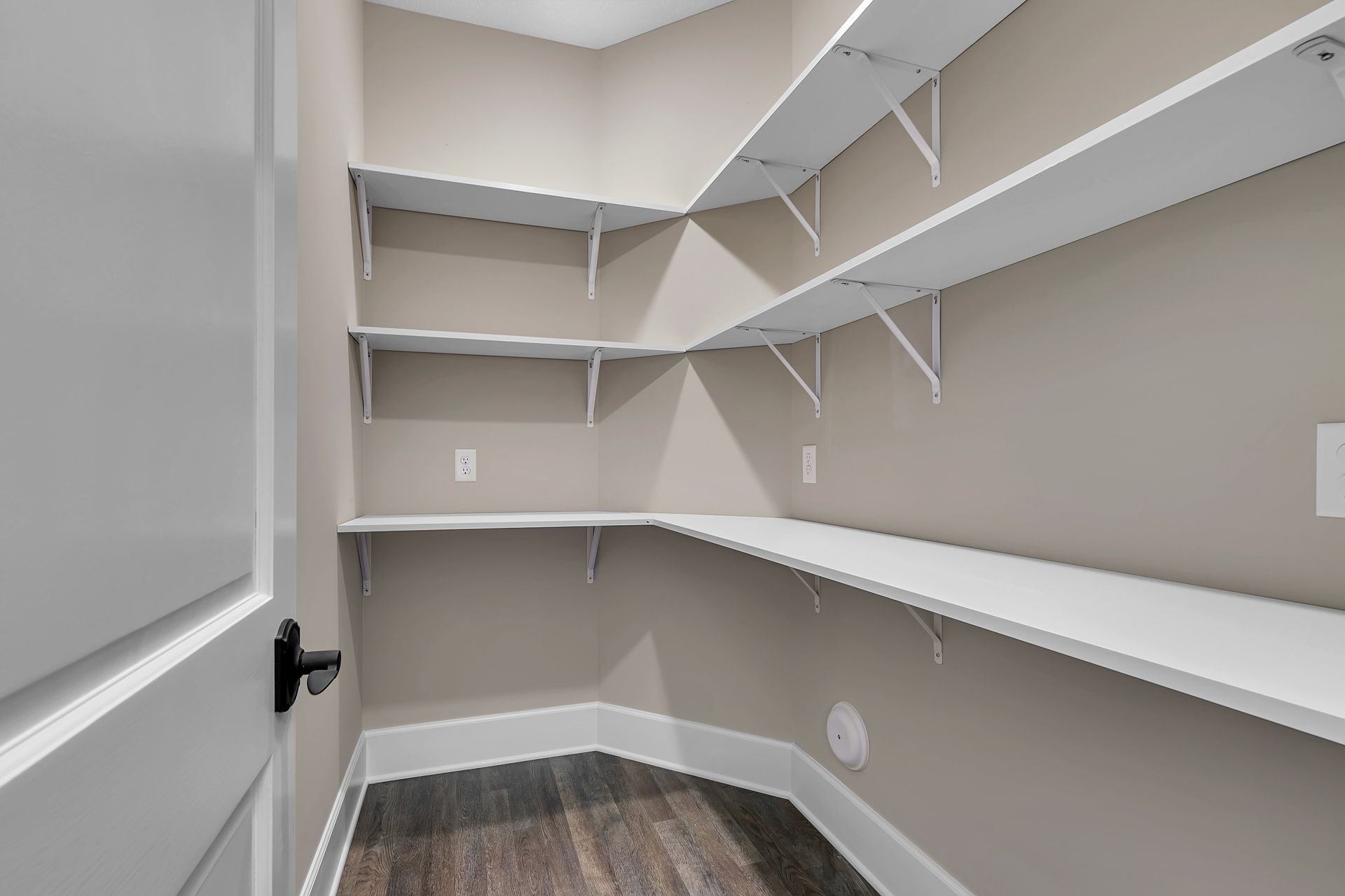 A walk in closet with lots of shelves and a door.
