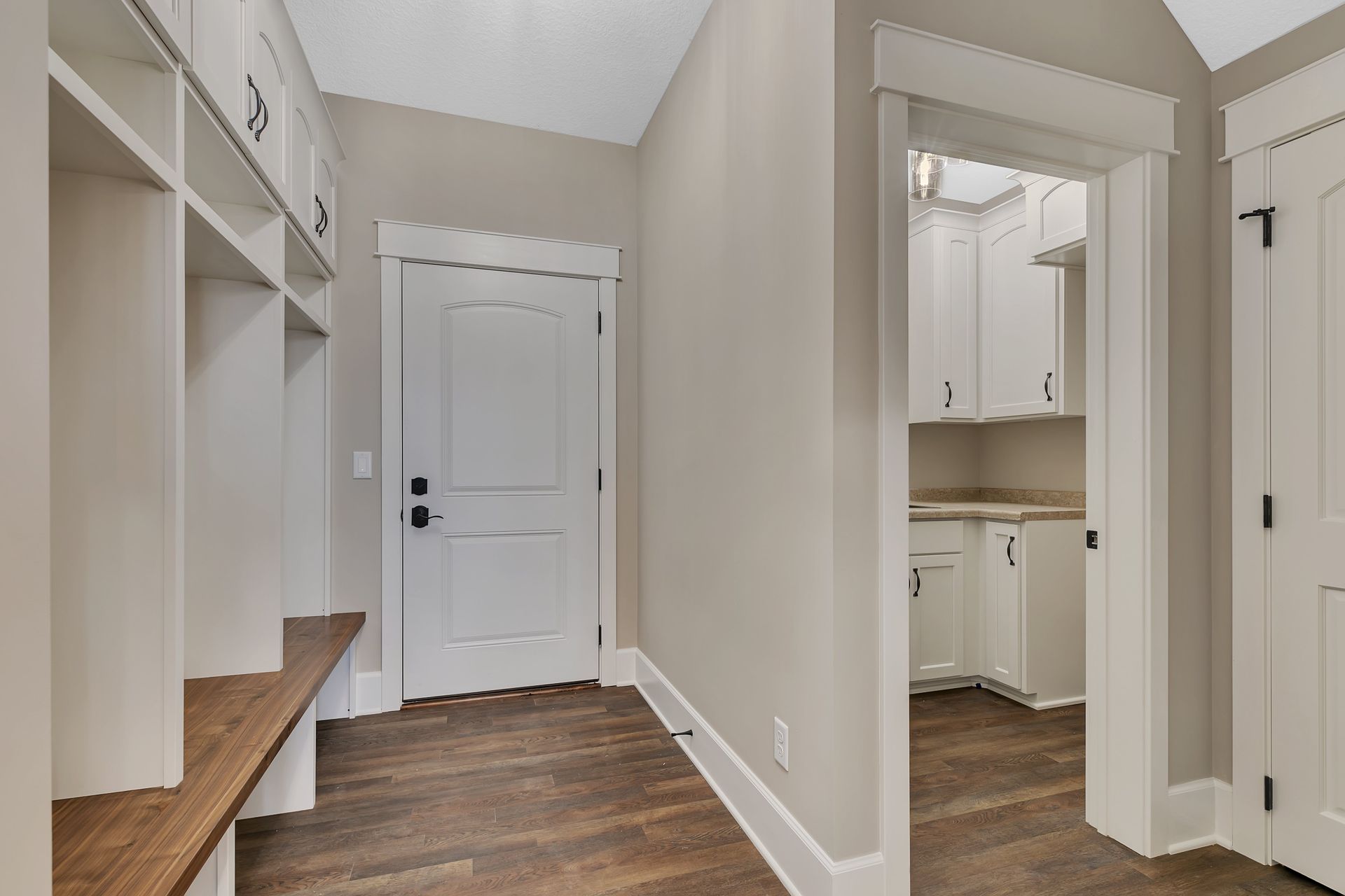 A hallway with hardwood floors and white cabinets in a house.
