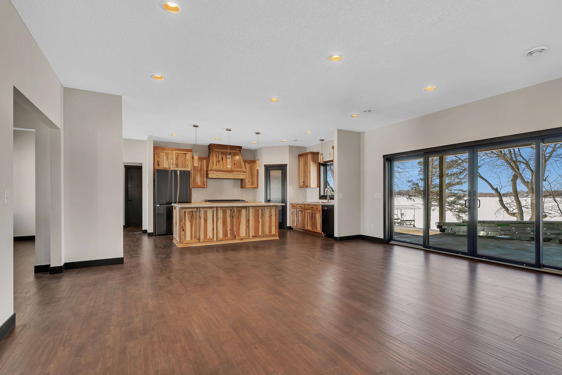 A large empty room with hardwood floors and a kitchen.