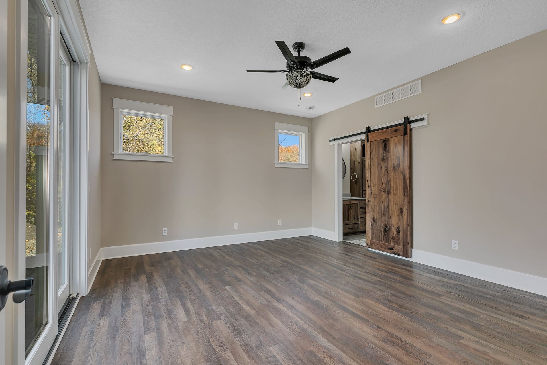 An empty room with a ceiling fan and a sliding barn door.