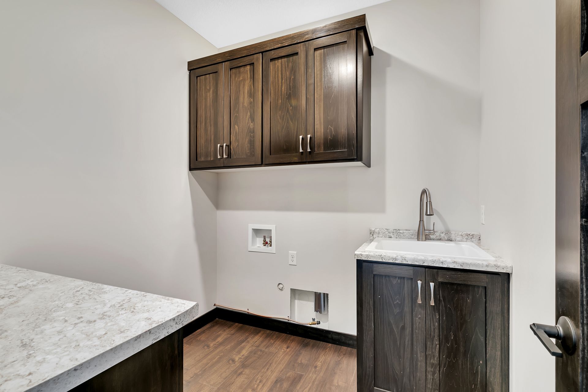 A laundry room with wooden cabinets and a sink.