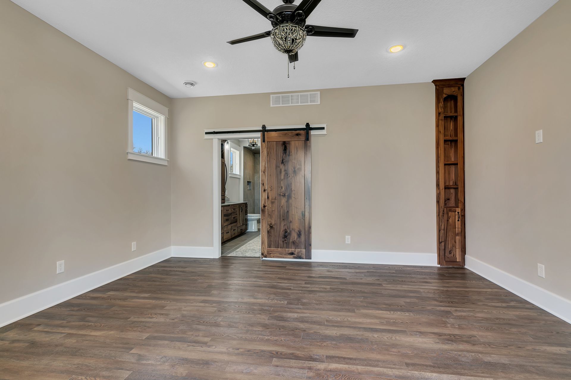 An empty room with a sliding barn door and a ceiling fan.