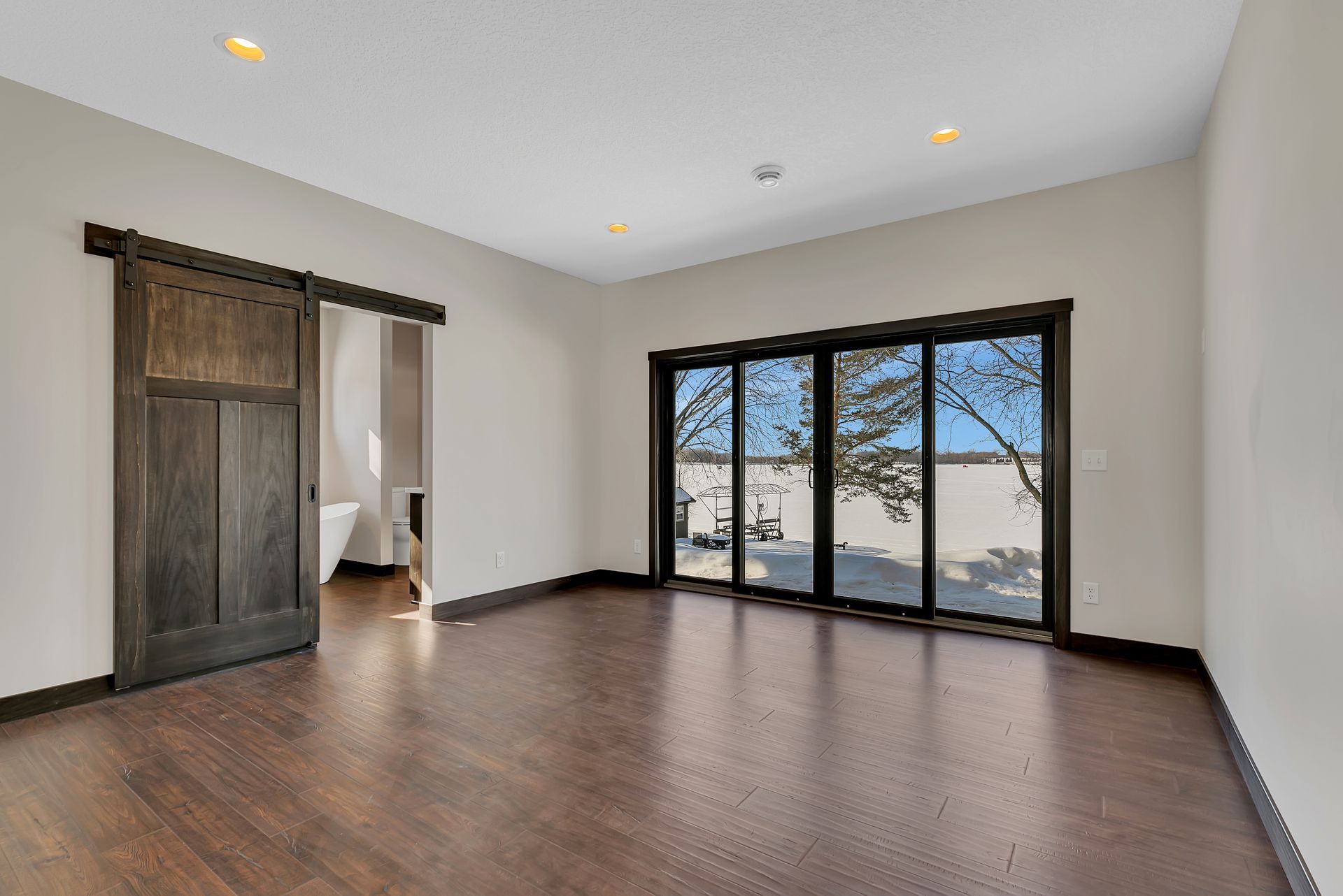 A large empty room with sliding glass doors and hardwood floors.