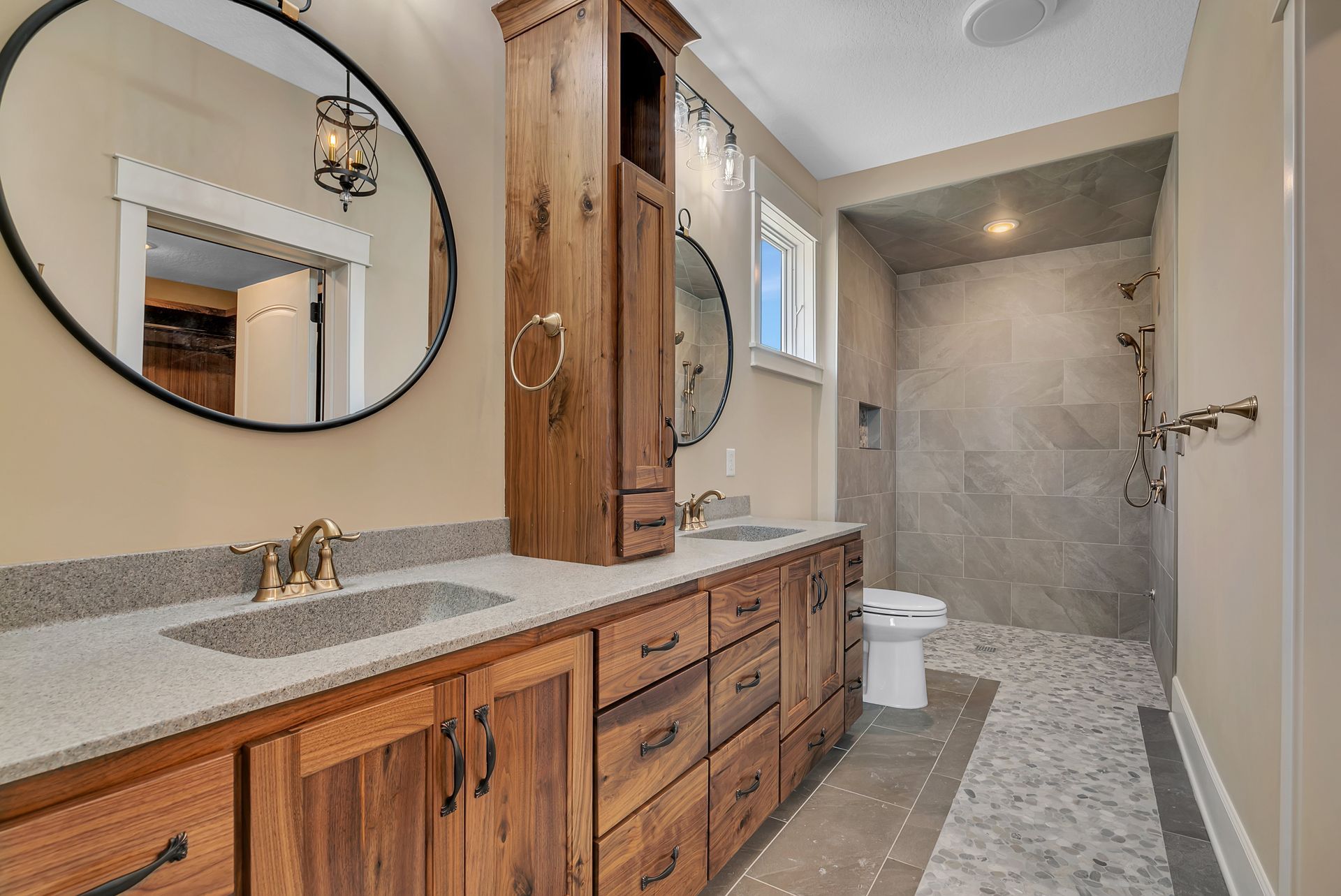 A bathroom with two sinks , a toilet and a walk in shower.