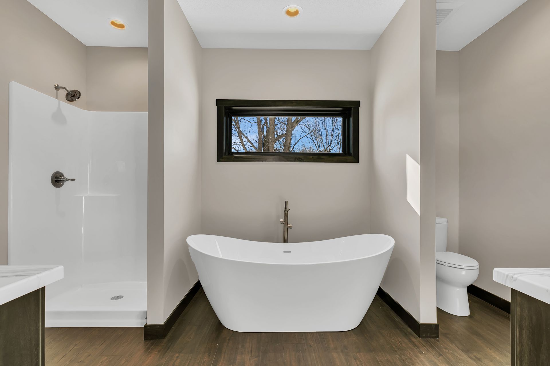 A bathroom with a tub , toilet , shower and window.