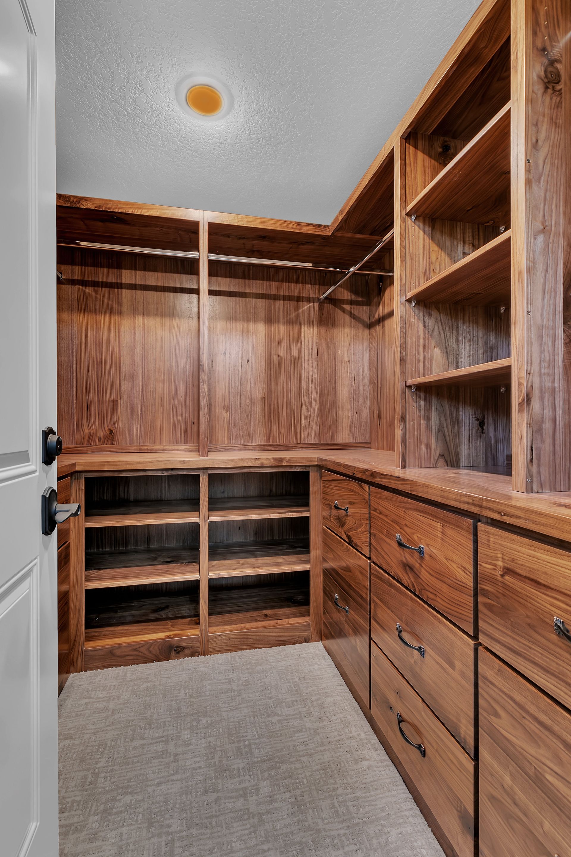 A walk in closet with wooden shelves and drawers.