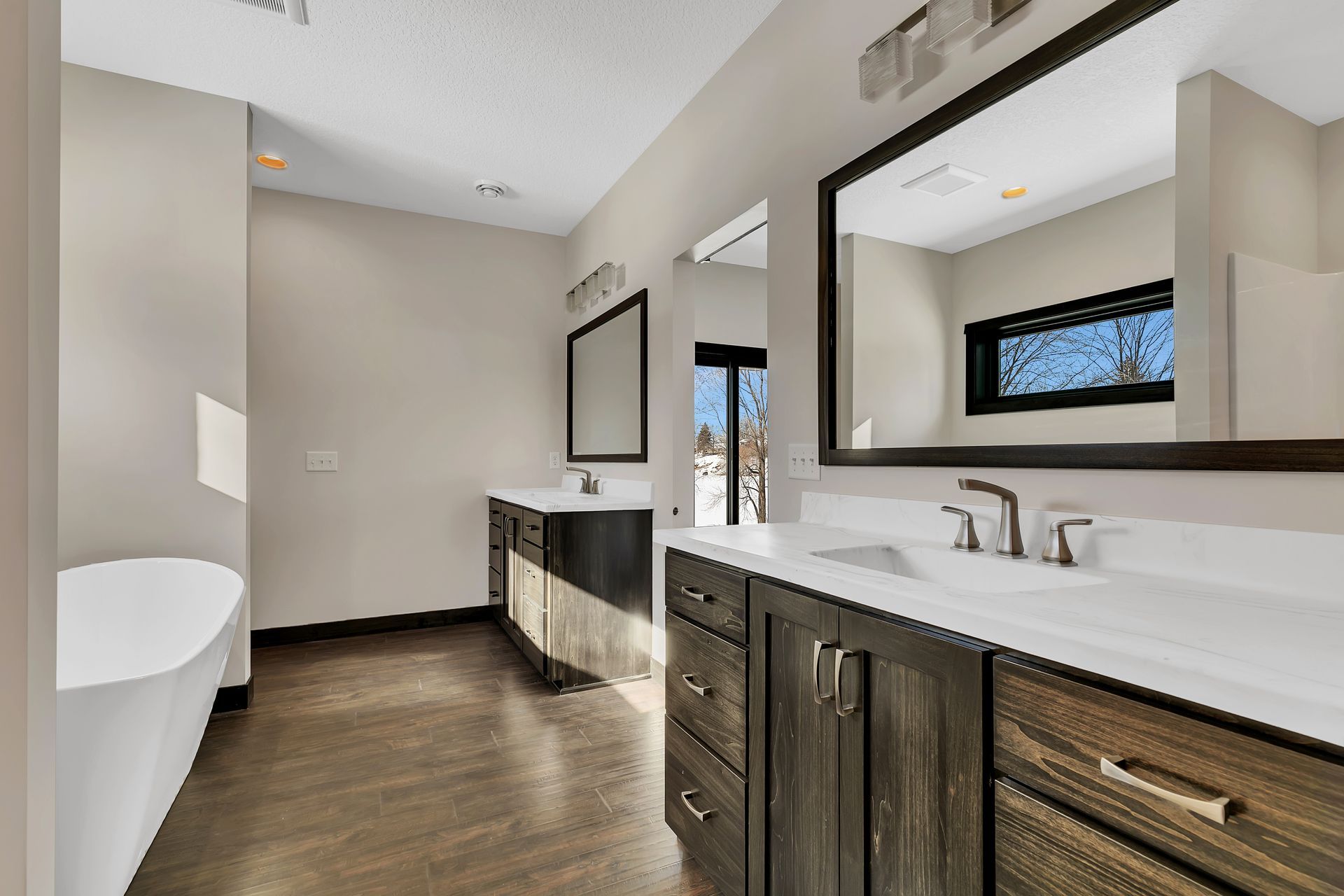 A bathroom with two sinks , two mirrors and a tub.
