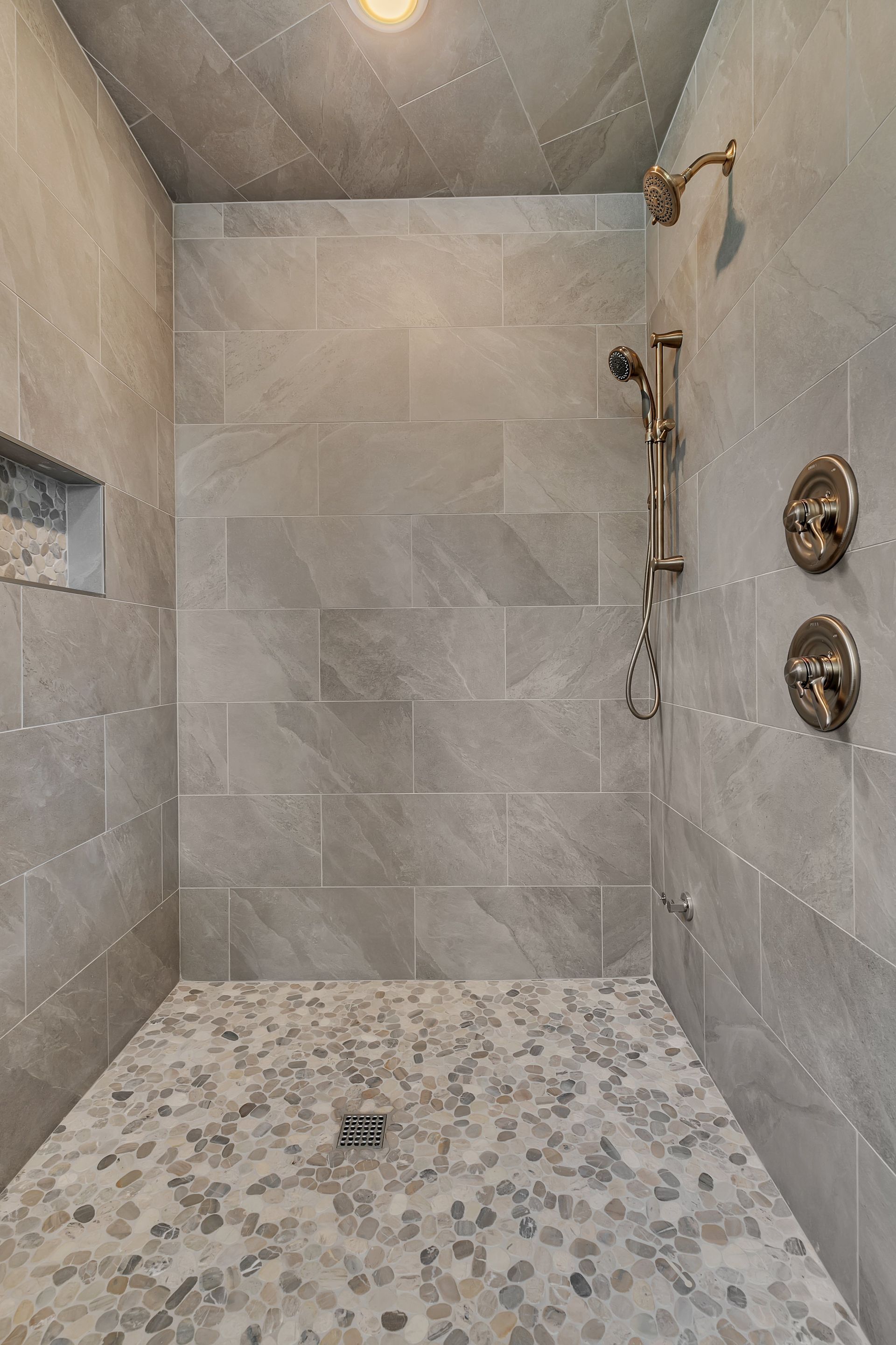 A walk in shower with a tiled floor and a shower head.