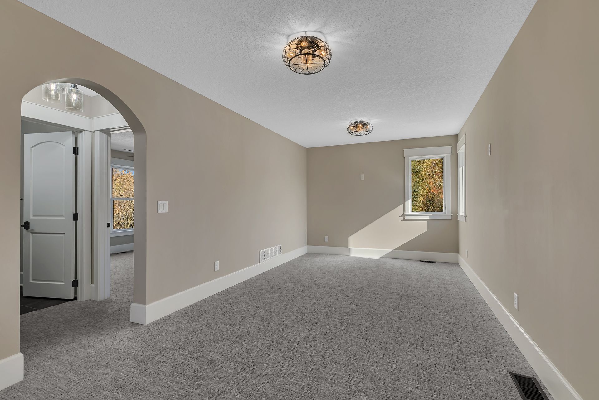A large empty room with a carpeted floor and a window.
