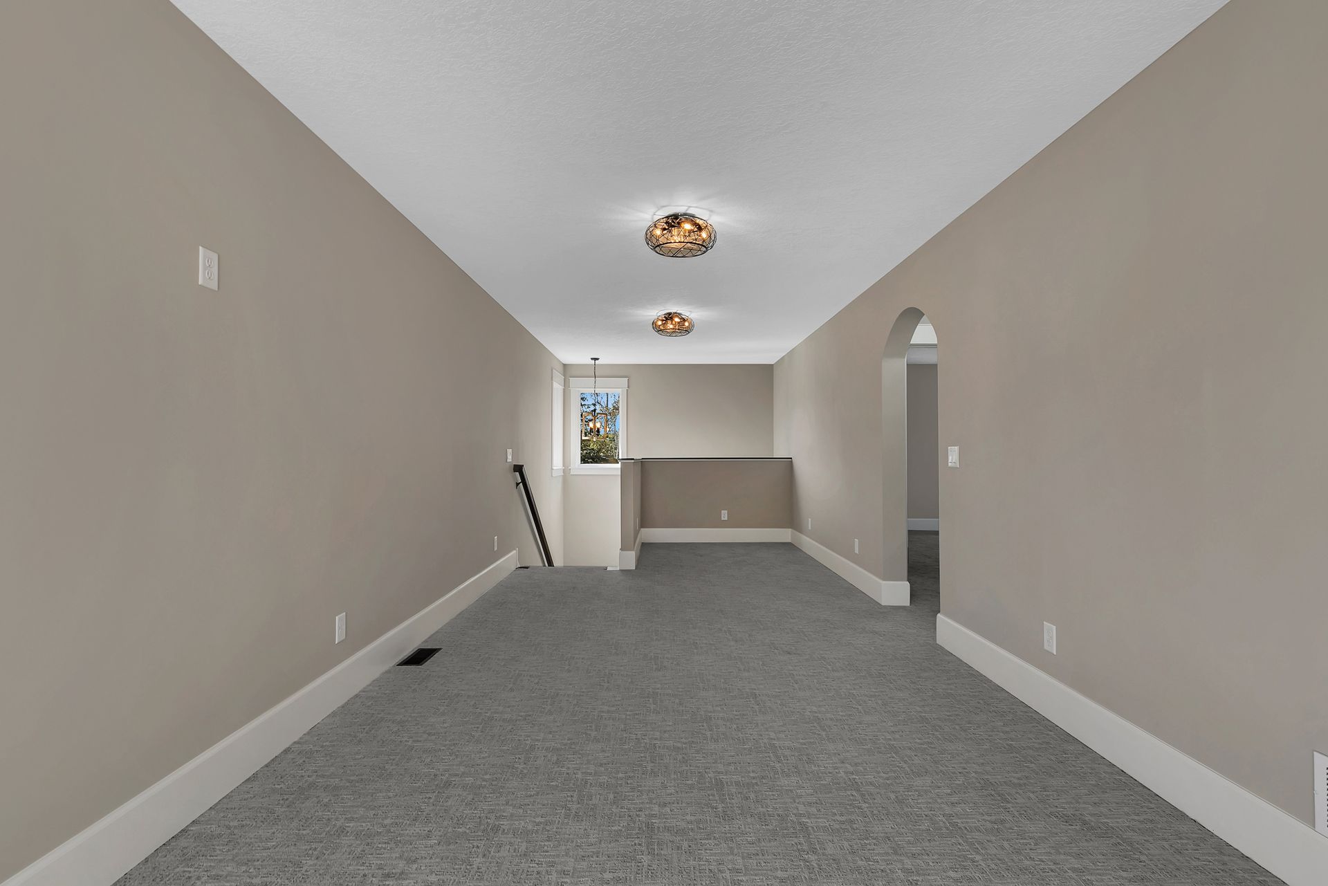 An empty room with a carpeted floor and beige walls.