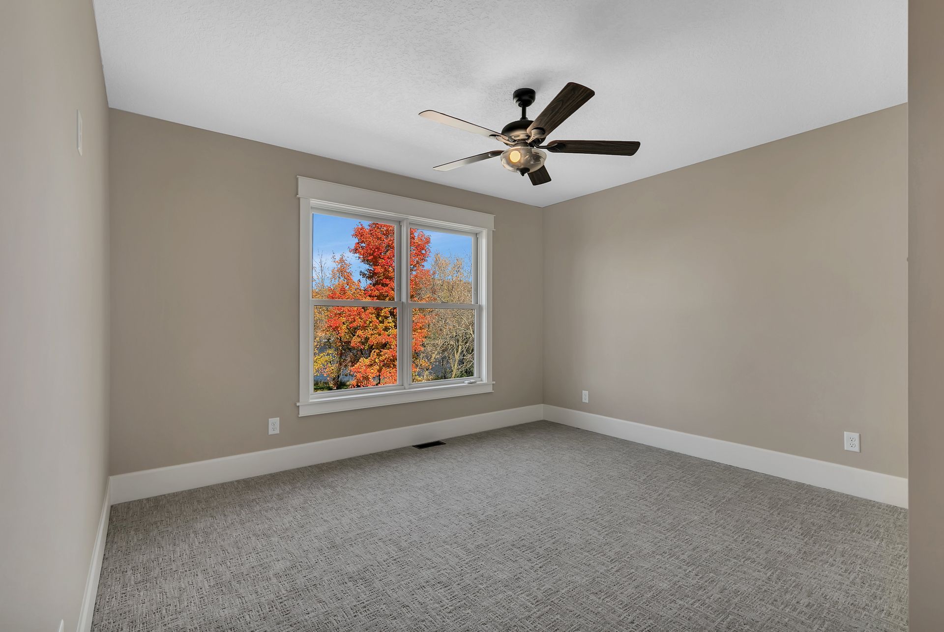 An empty bedroom with a ceiling fan and a window.