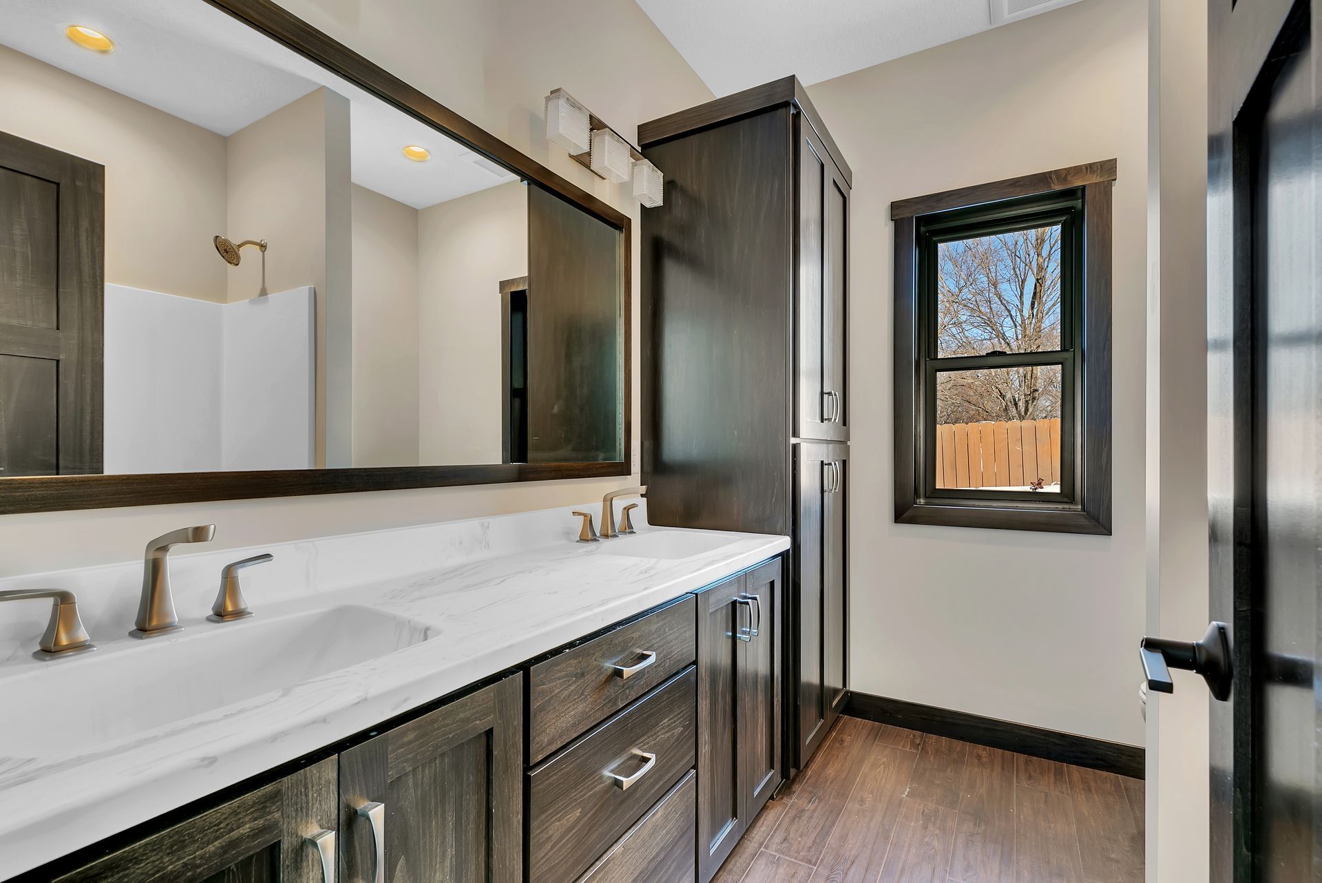 A bathroom with two sinks , a large mirror and a window.
