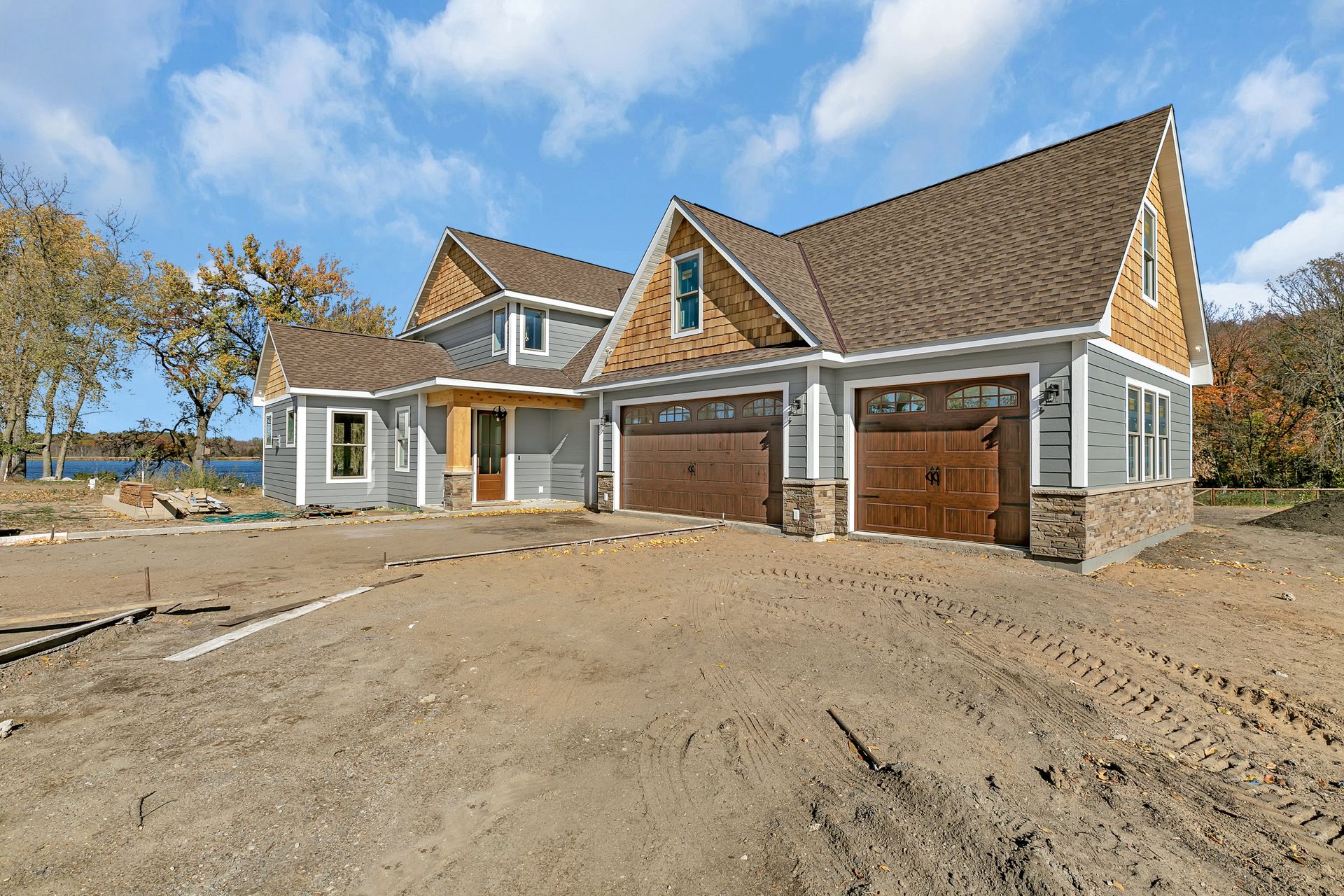 A large house with two garage doors is sitting on top of a dirt field.