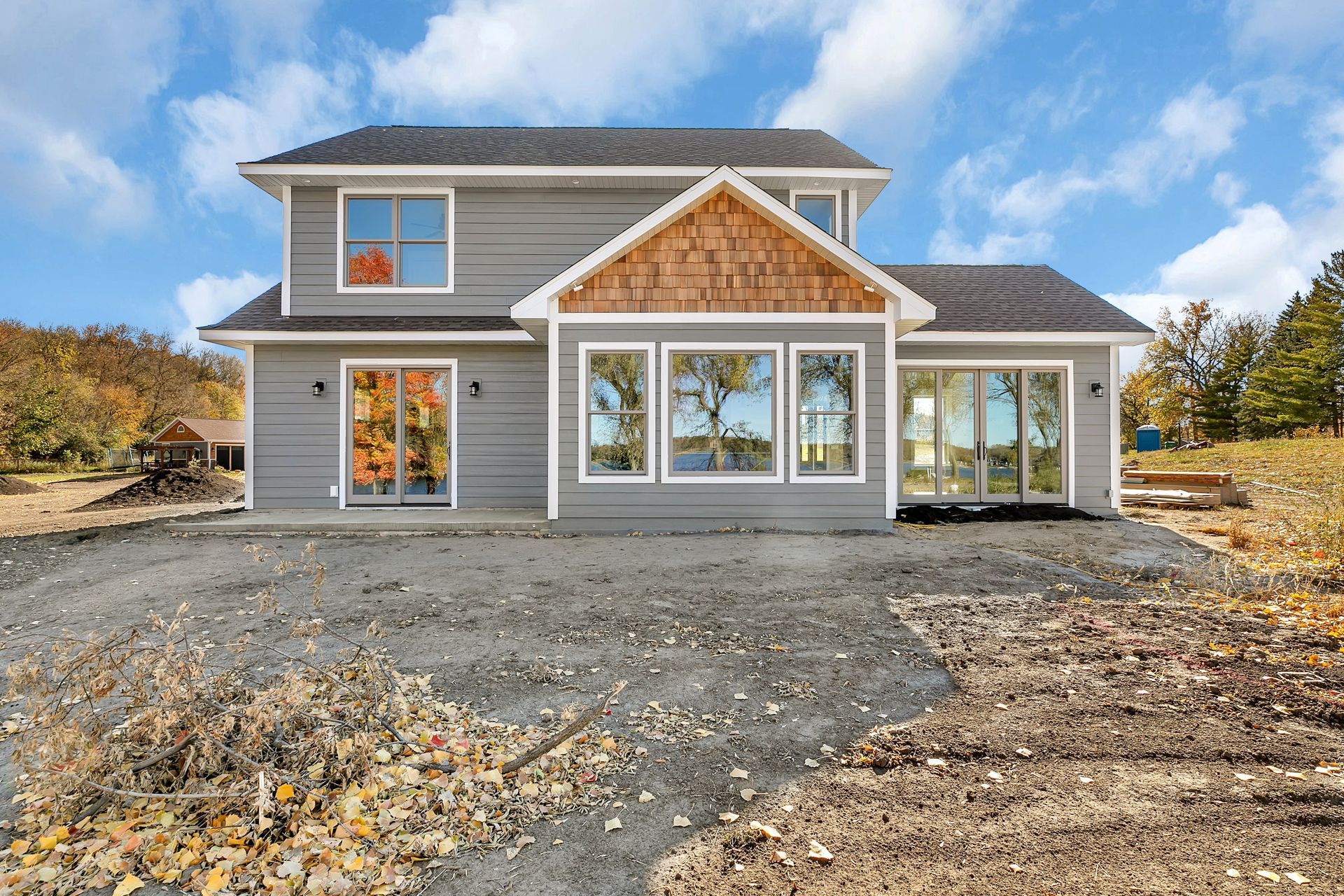 A large house with a lot of windows is sitting on top of a dirt field.
