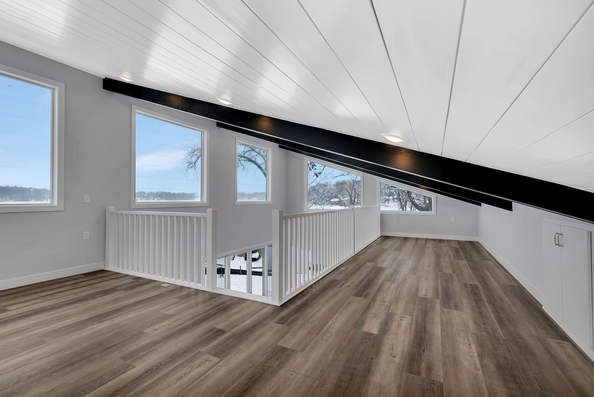 An empty attic with hardwood floors and a balcony