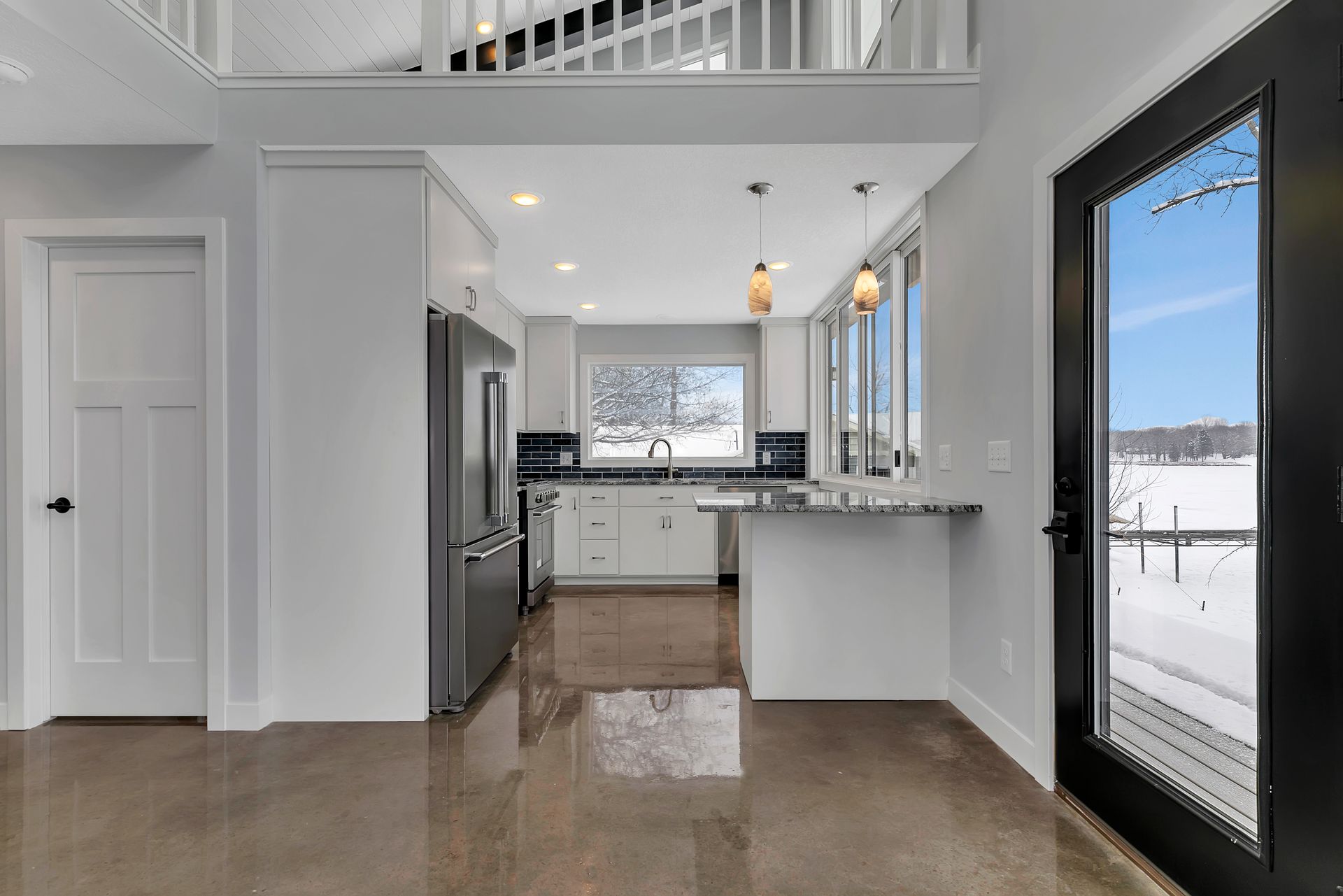 A kitchen with white cabinets and stainless steel appliances and a large window.
