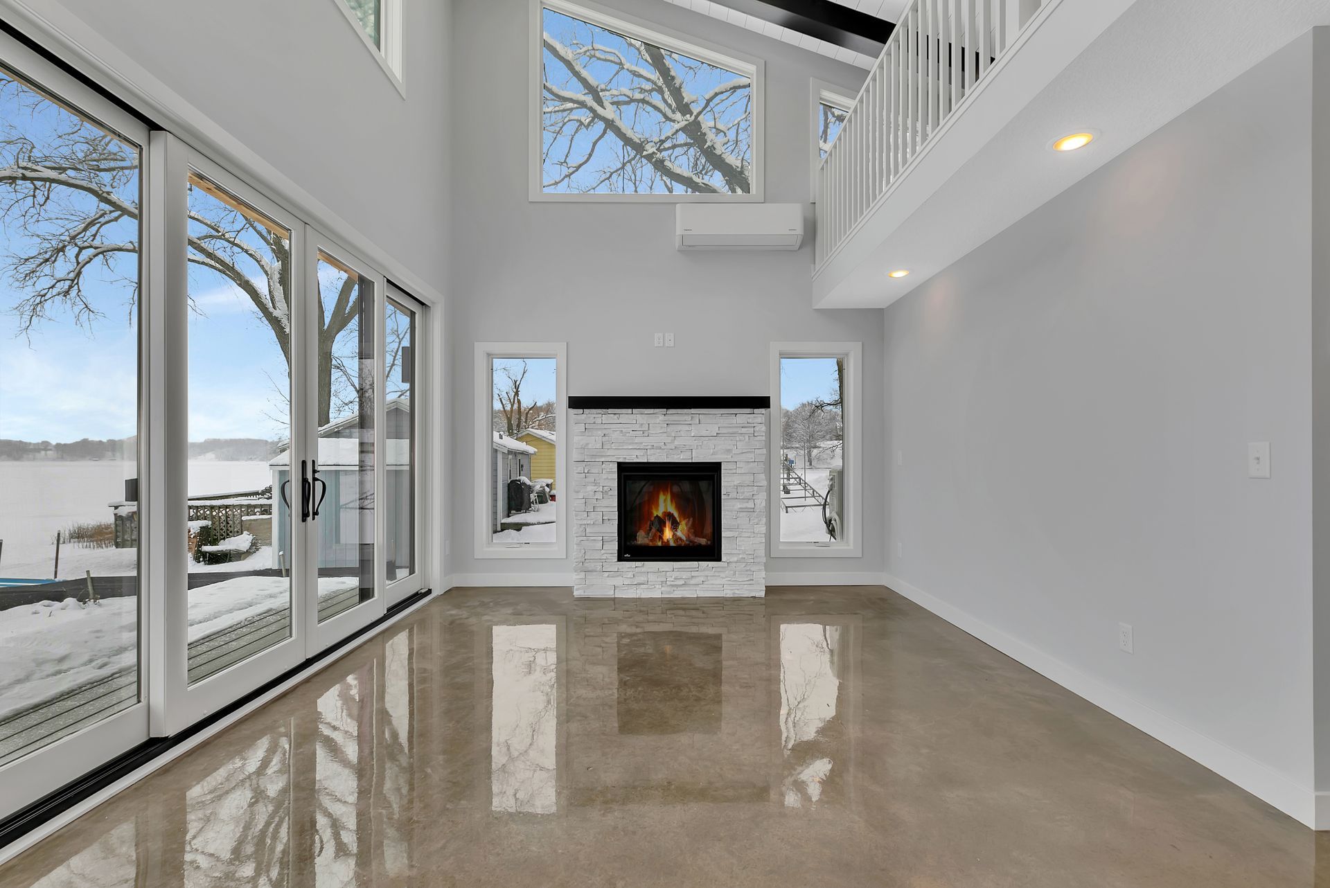 An empty living room with a fireplace and lots of windows.
