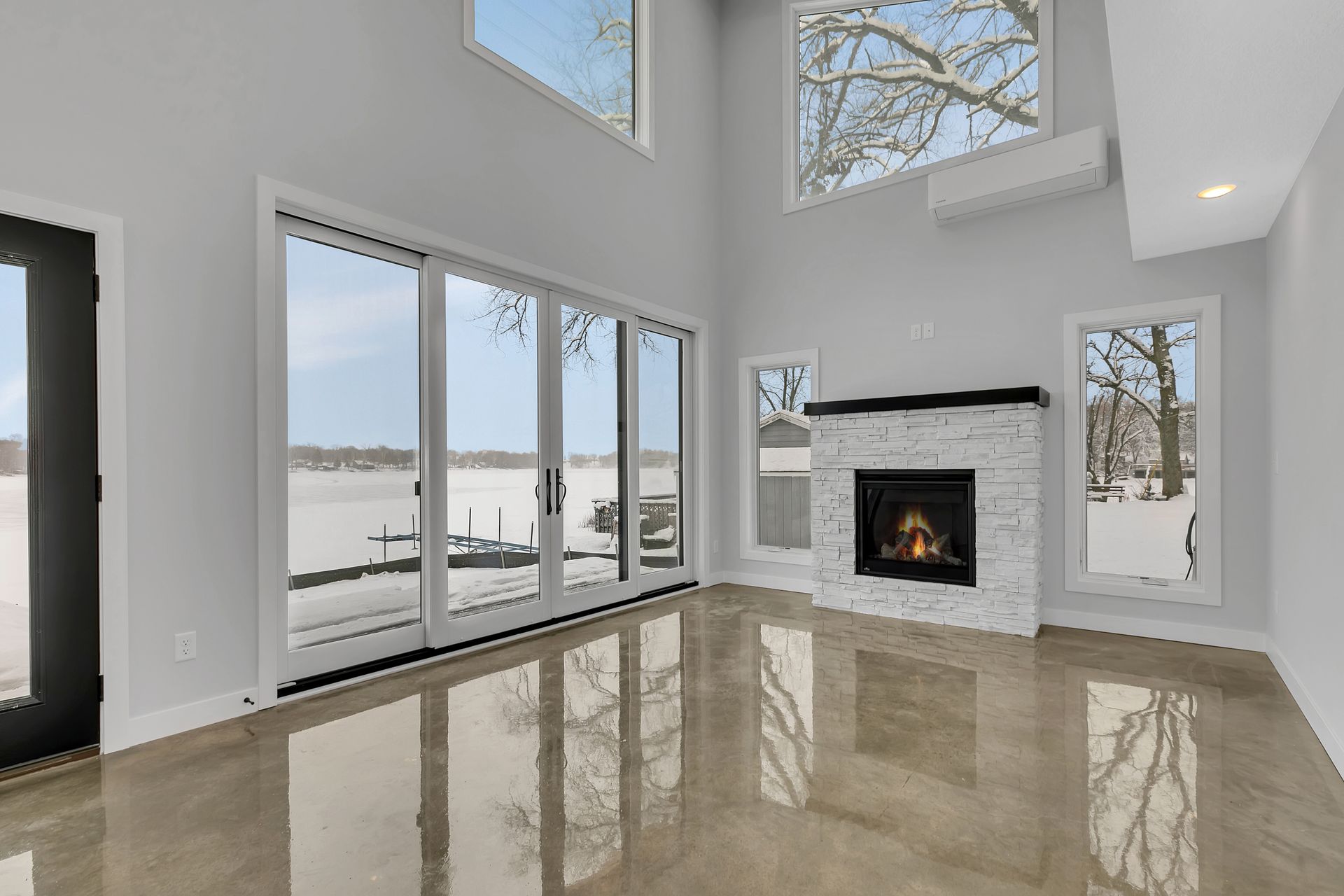 An empty living room with a fireplace and sliding glass doors.