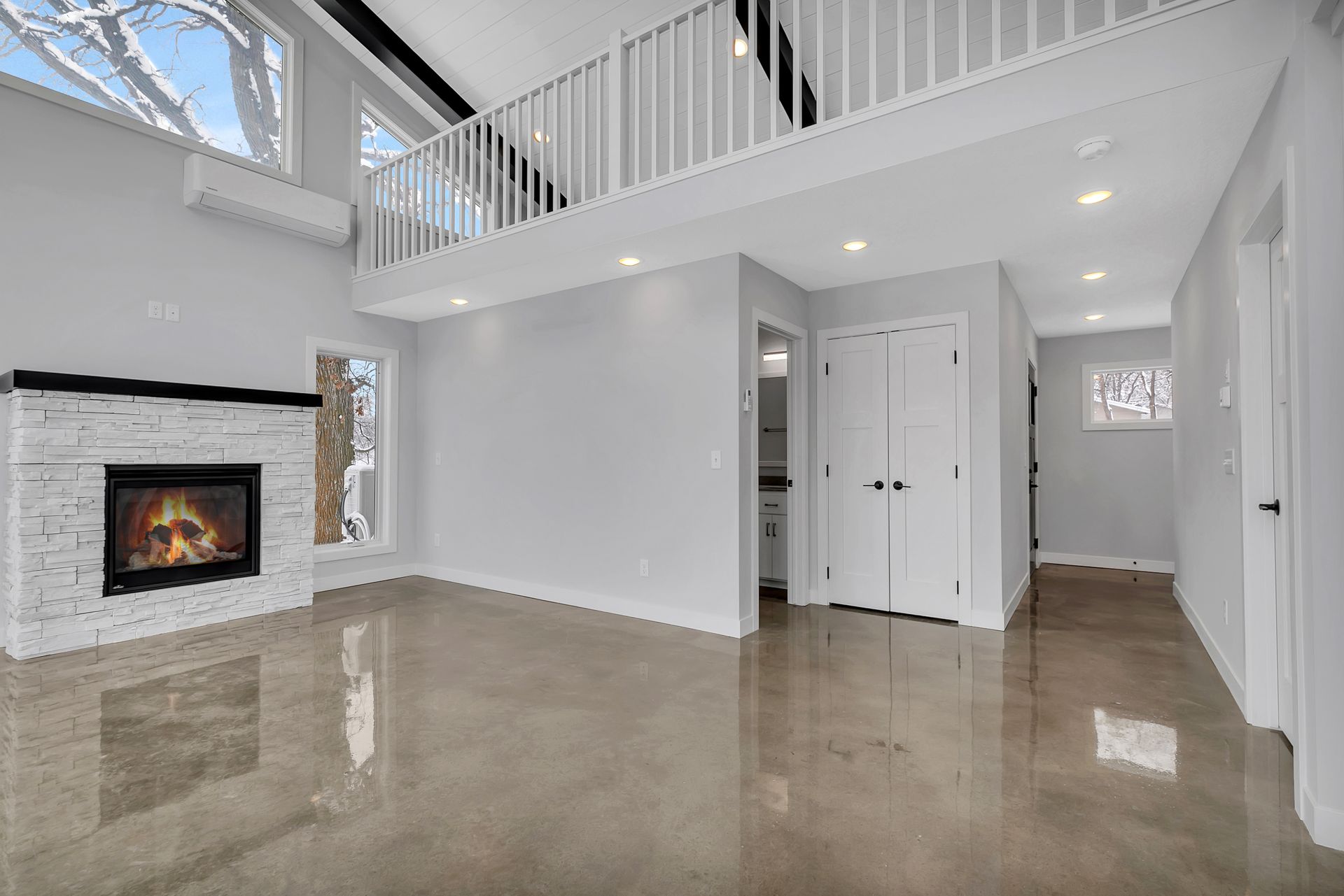 An empty living room with a fireplace and a balcony.