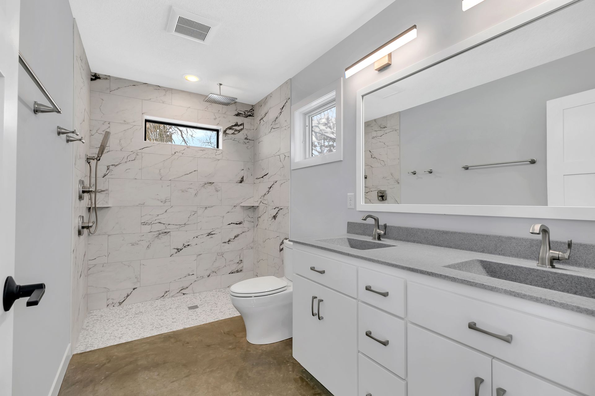A bathroom with a toilet , sink , mirror and walk in shower.