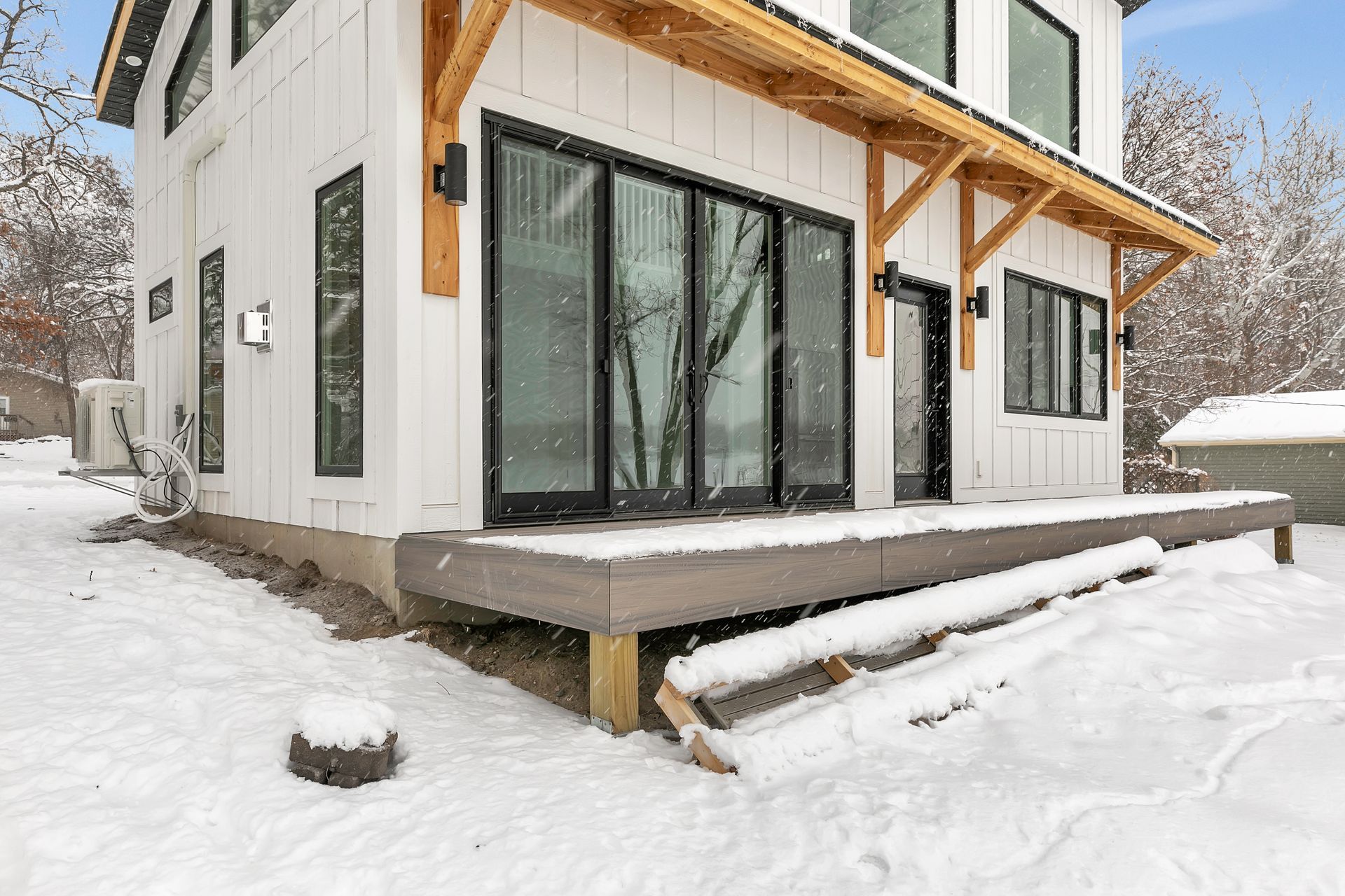 A white house with a large deck in the snow.