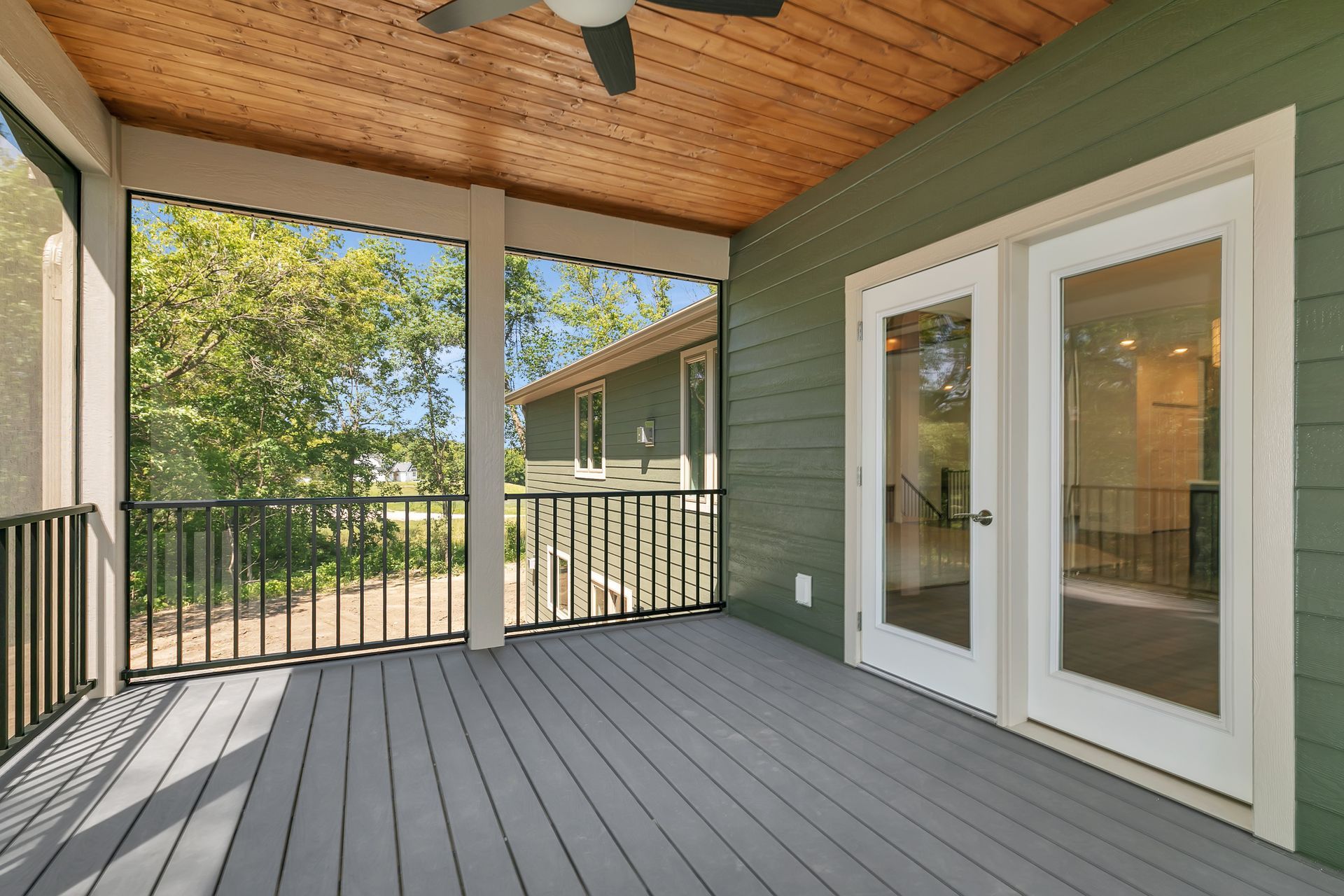 A screened in porch with a ceiling fan and sliding glass doors