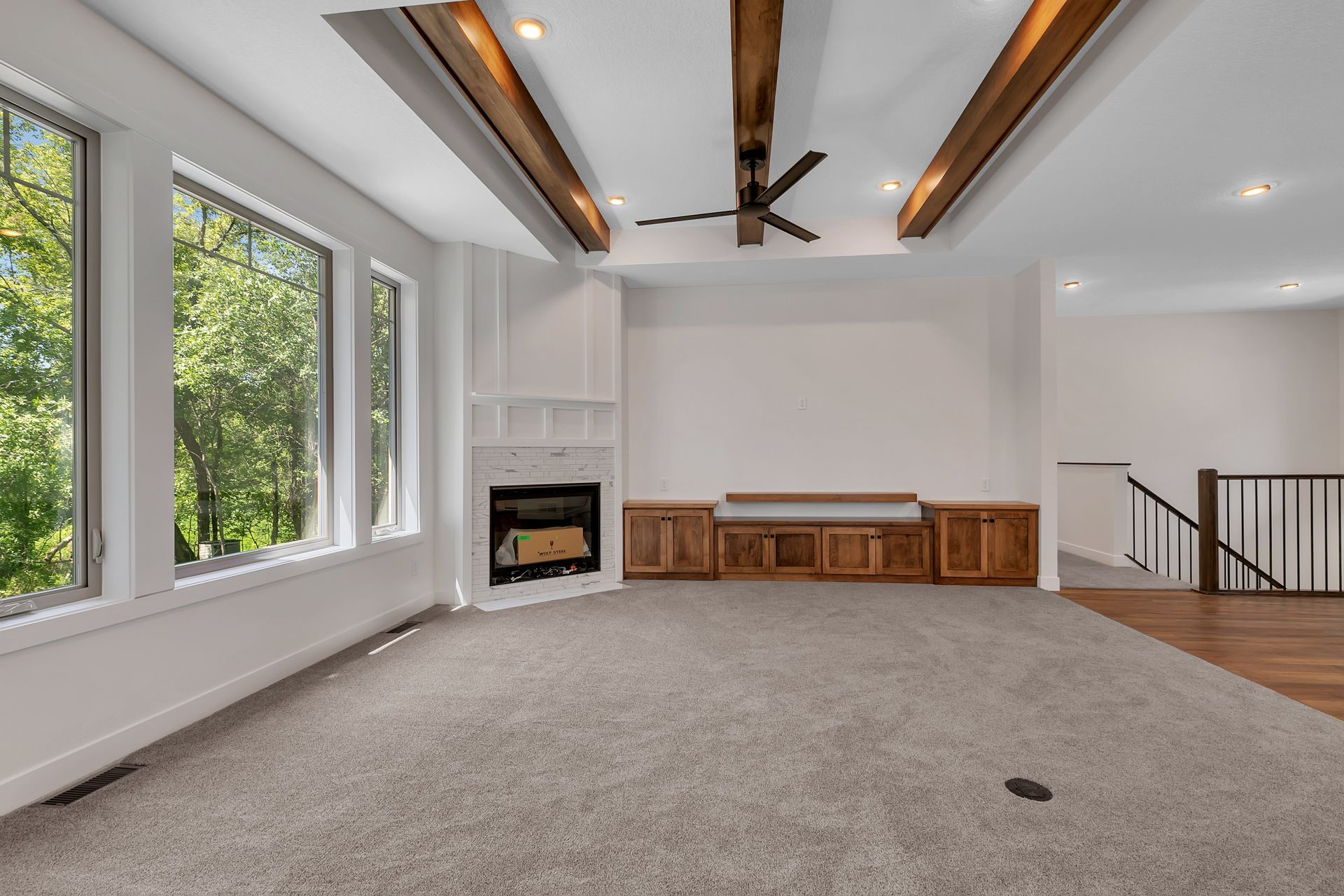 An empty living room with a fireplace and a ceiling fan
