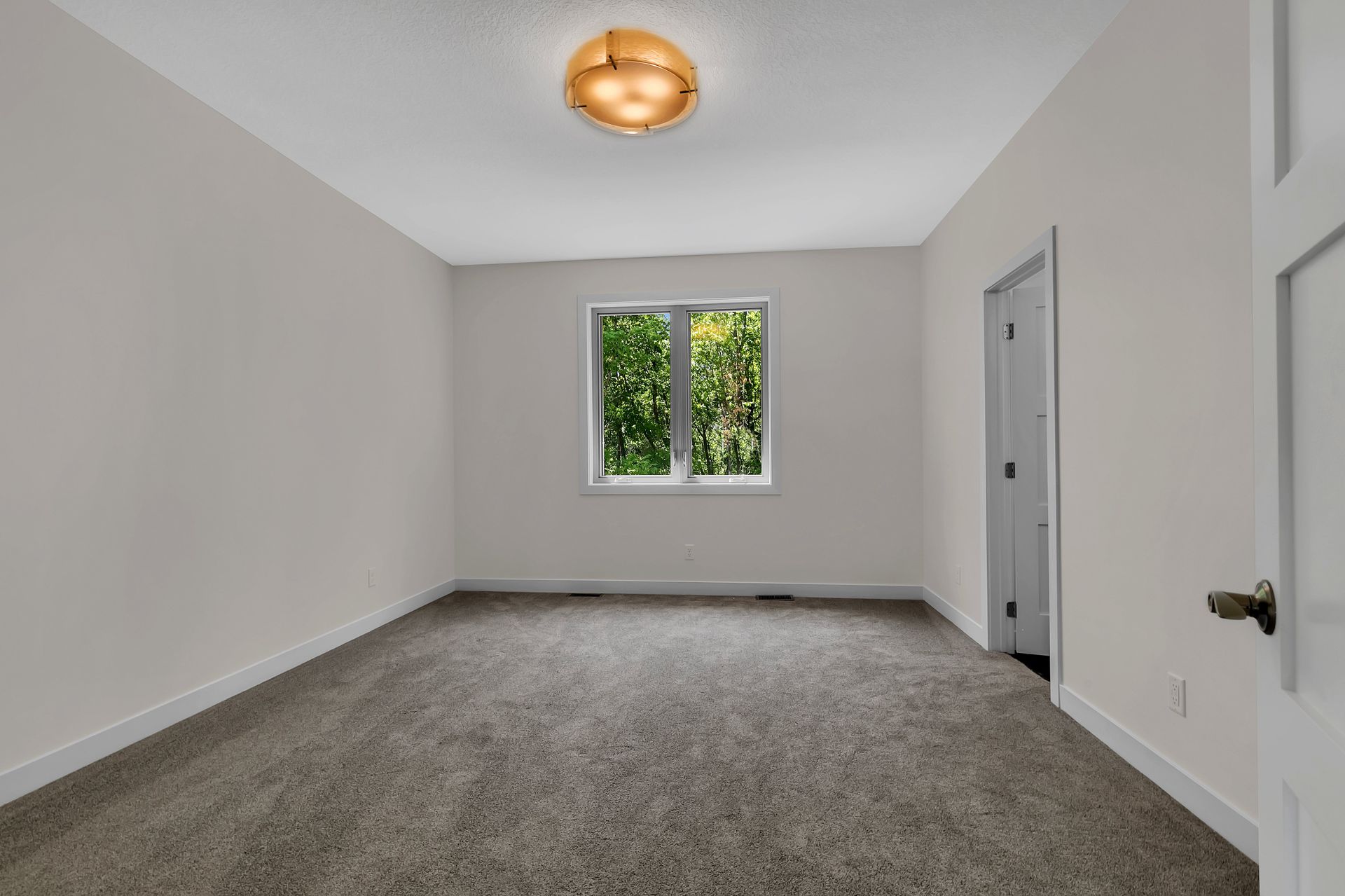 An empty room with a window and a ceiling light.