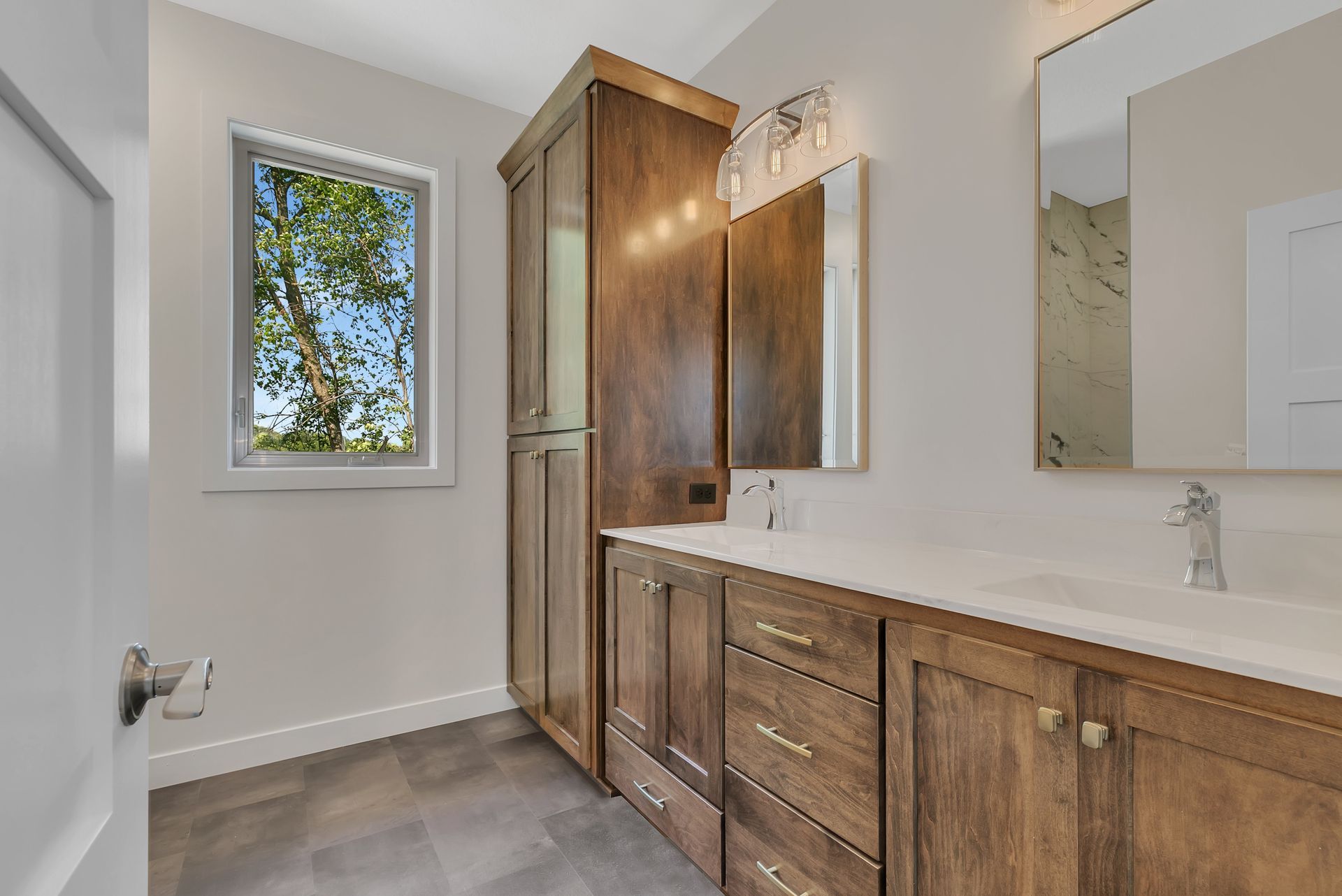 A bathroom with two sinks , a mirror and a window.