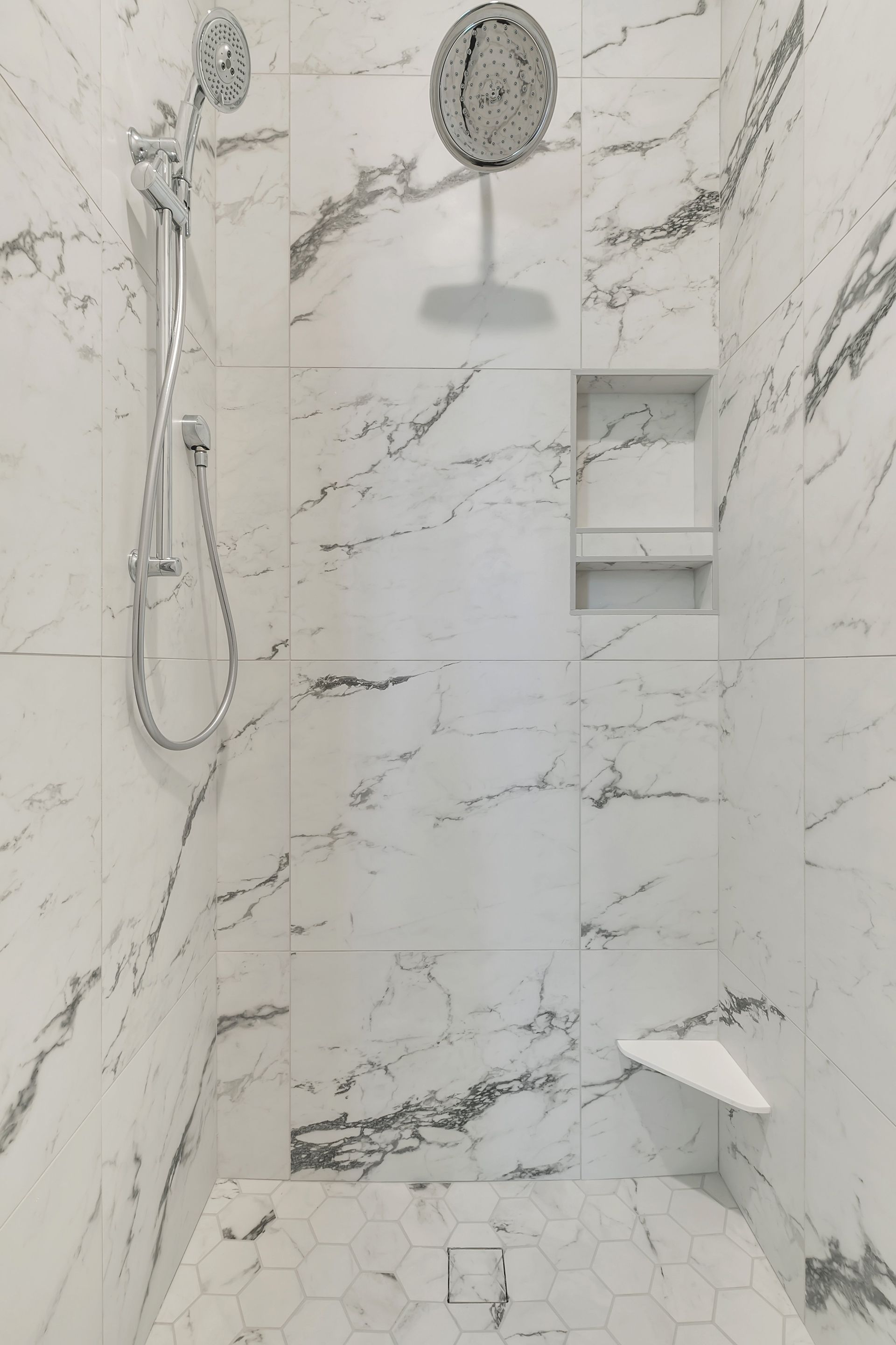 A bathroom with marble tiles and a shower with a clock on the wall.