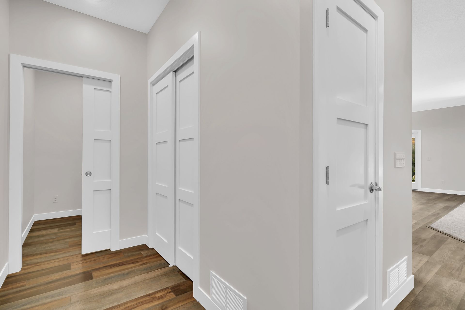 A hallway with white doors and hardwood floors in a house.