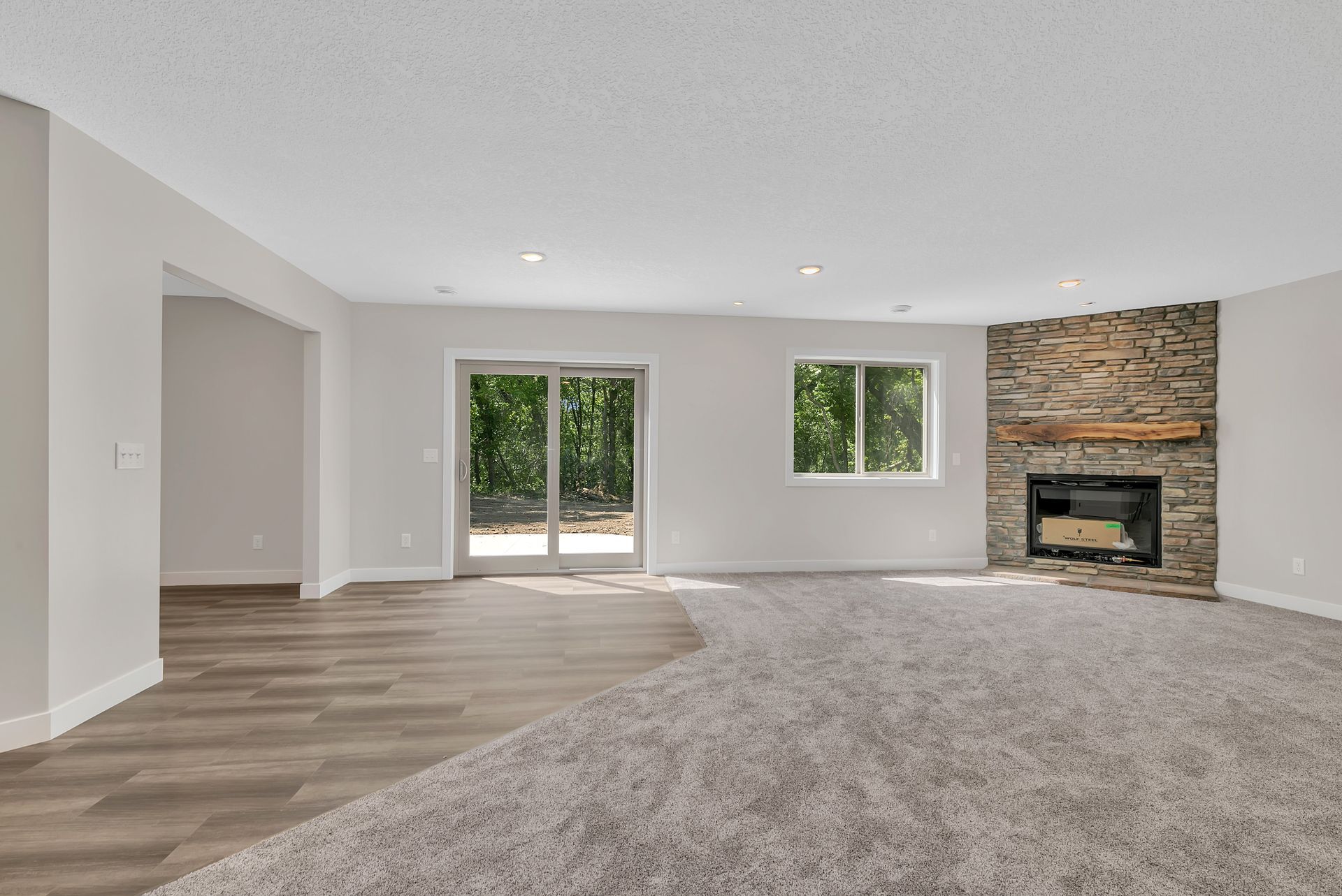 An empty living room with a fireplace and sliding glass doors.