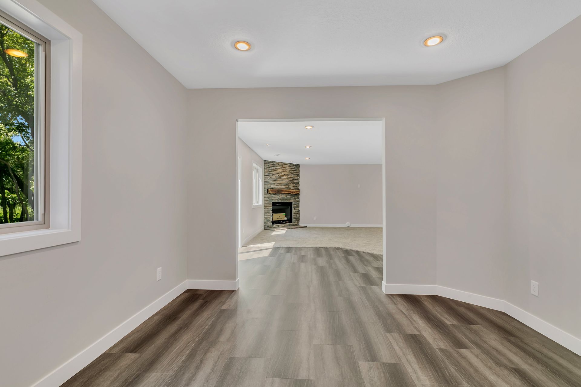 An empty living room with hardwood floors and a fireplace.