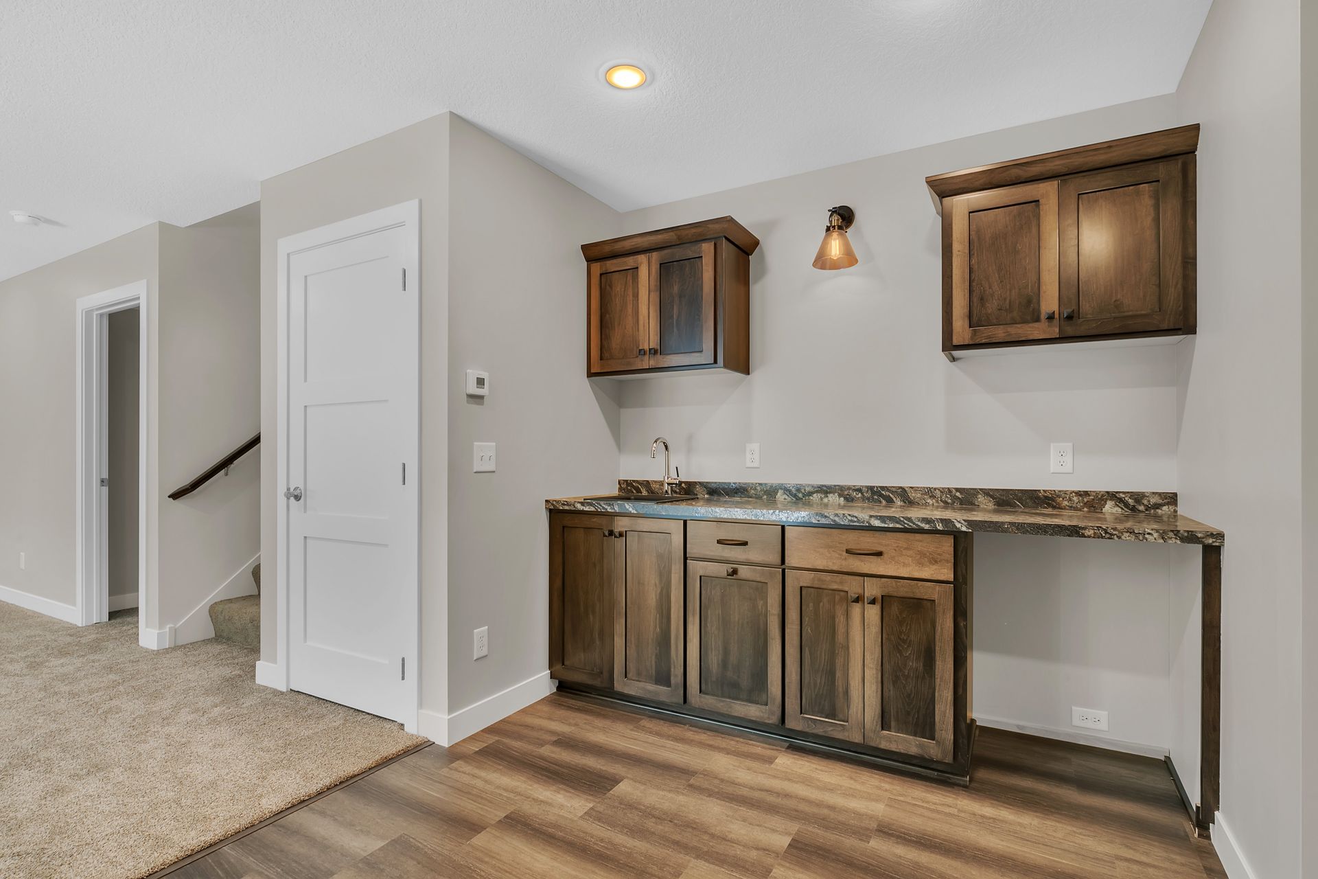 A kitchen in a basement with wooden cabinets and a sink.