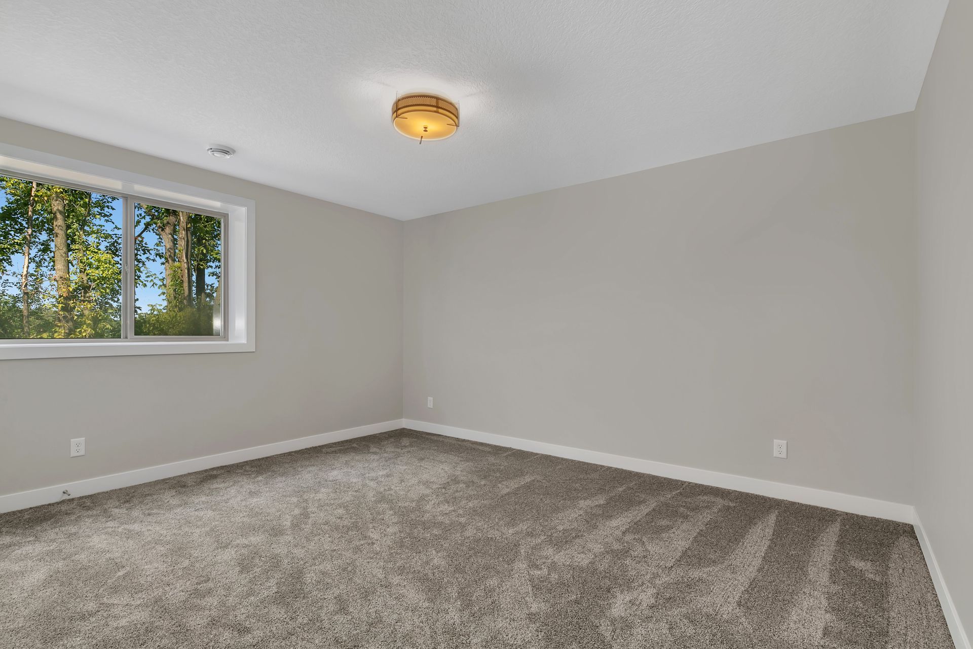 An empty room with a carpeted floor and a window.
