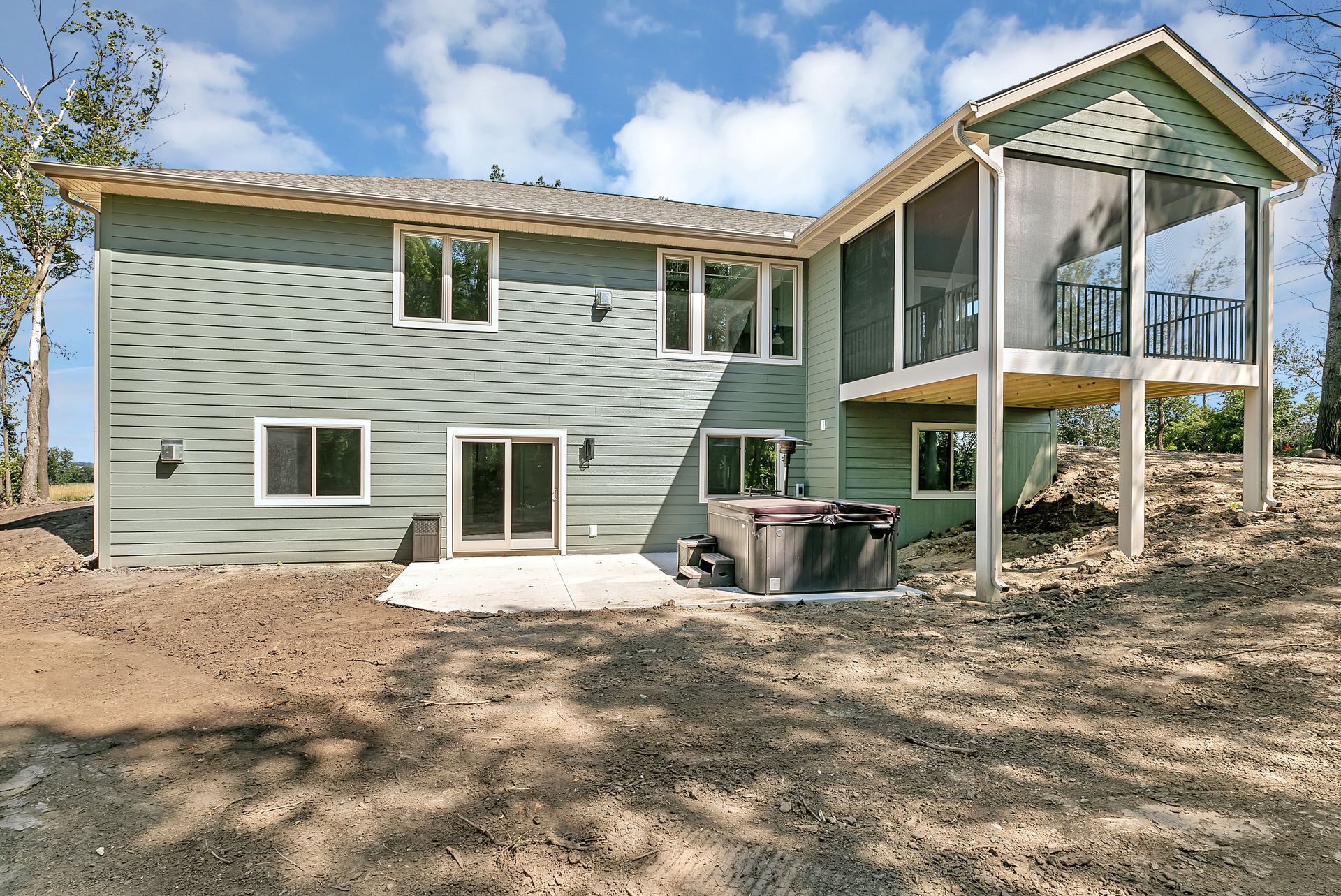 The back of a house with a screened in porch and a hot tub
