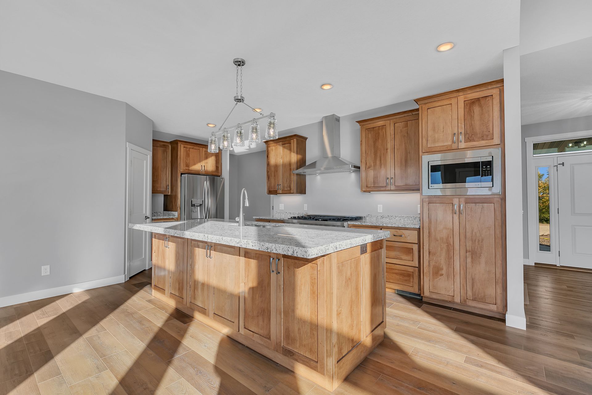 A kitchen with wooden cabinets , granite counter tops , stainless steel appliances and a large island.