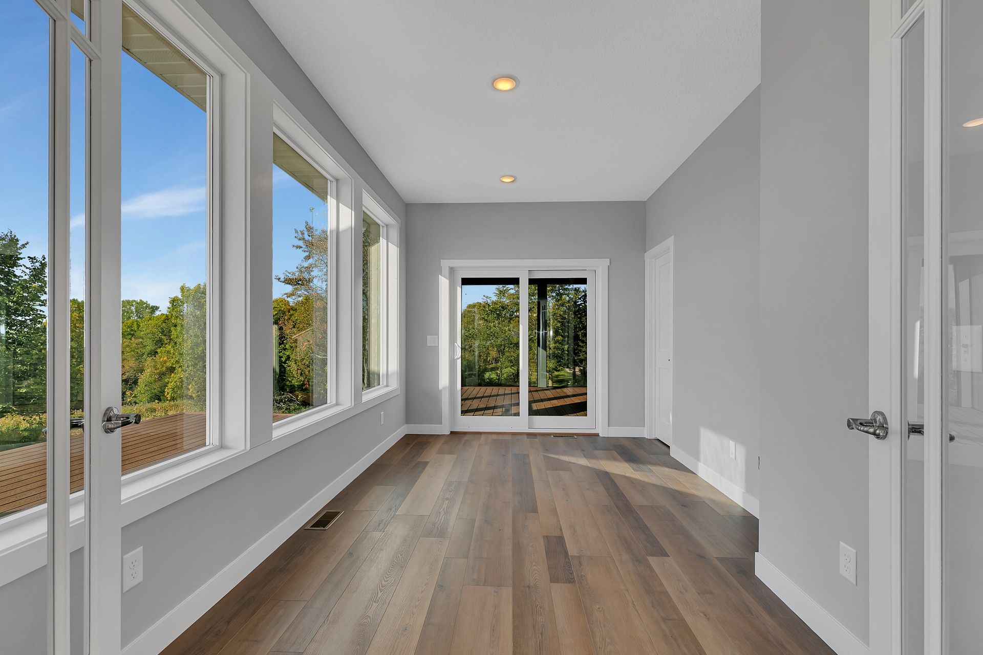 An empty room with hardwood floors and lots of windows.