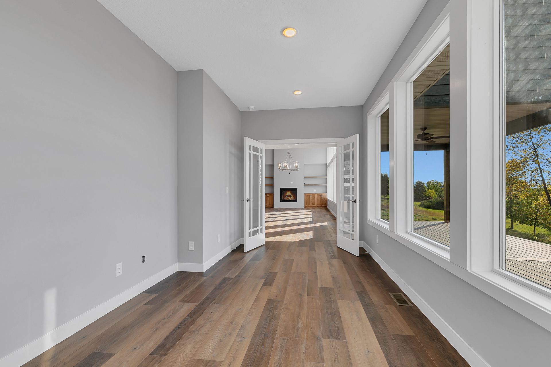A long hallway in a house with hardwood floors and lots of windows.