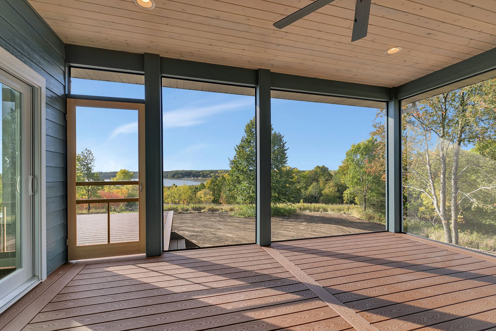 A screened in porch with a view of a lake and trees