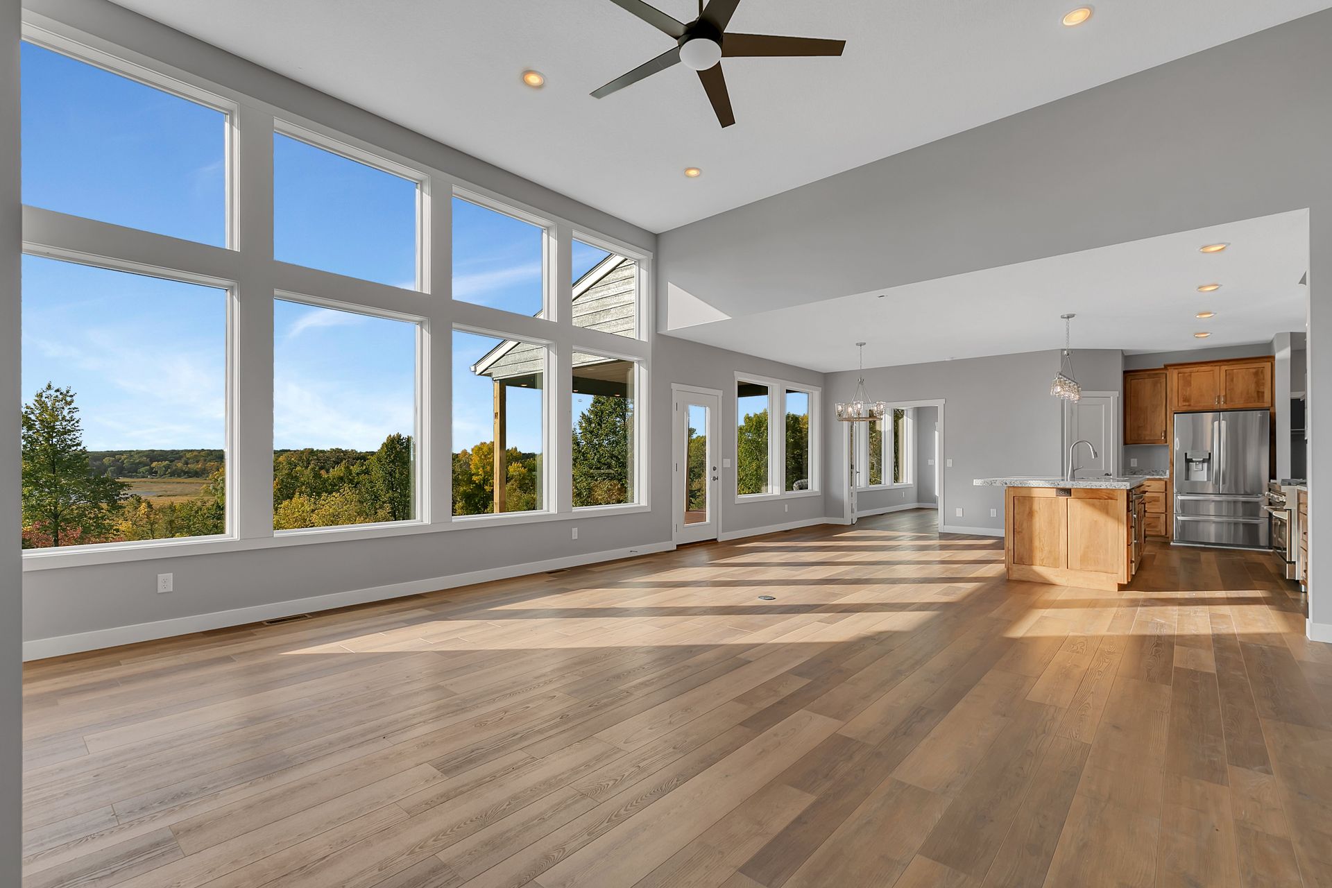 A large empty room with a lot of windows and a ceiling fan.