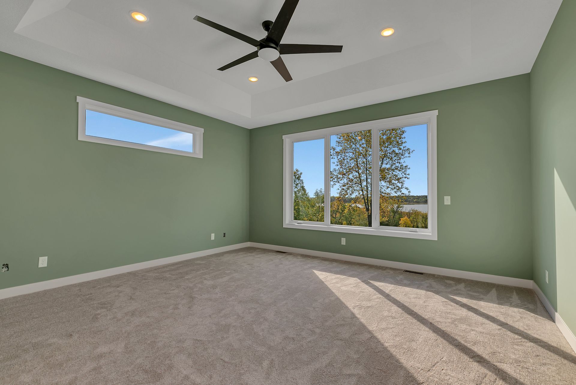 An empty bedroom with green walls and a ceiling fan.