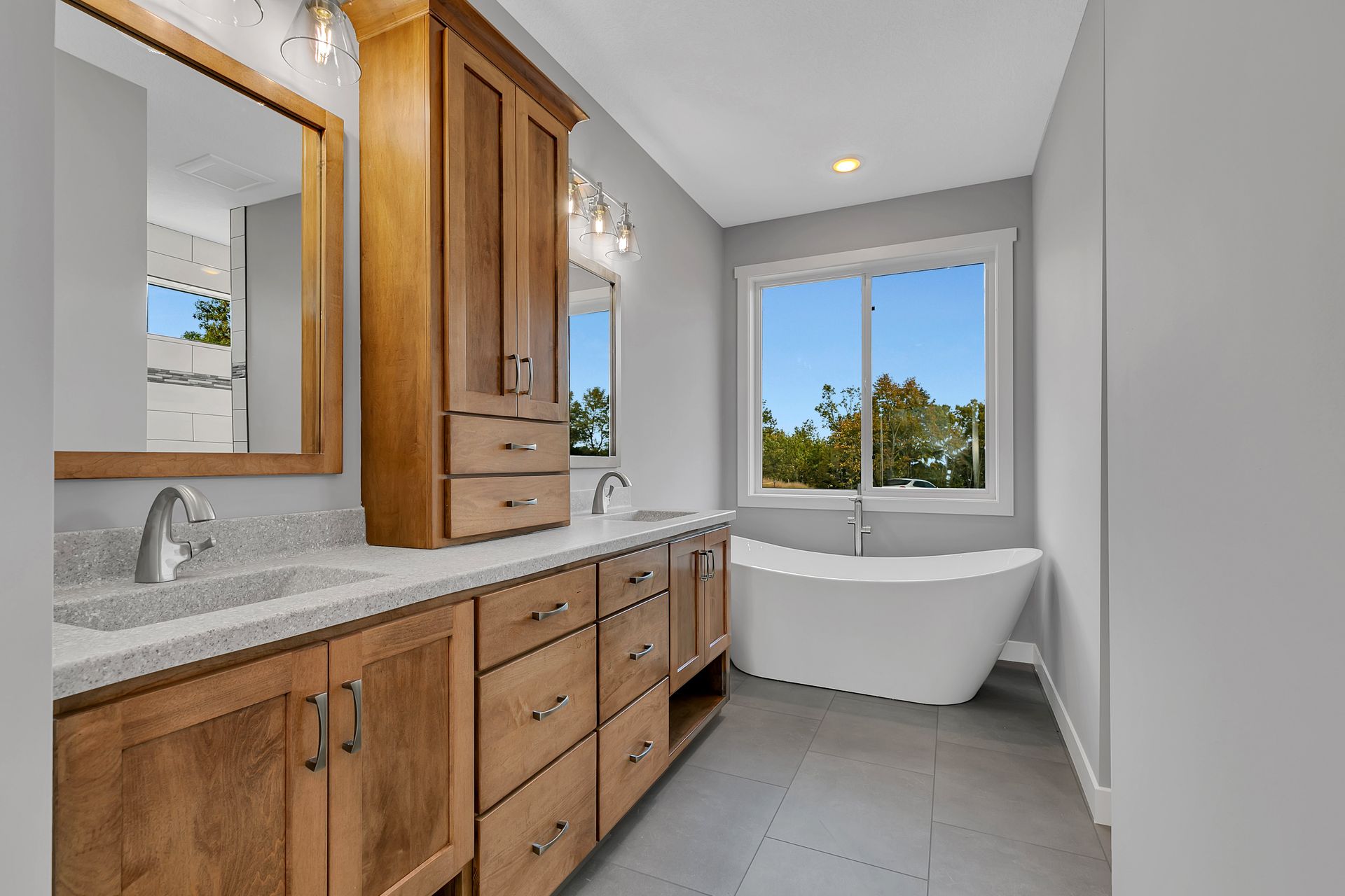 A bathroom with two sinks , a tub , a mirror and a window.