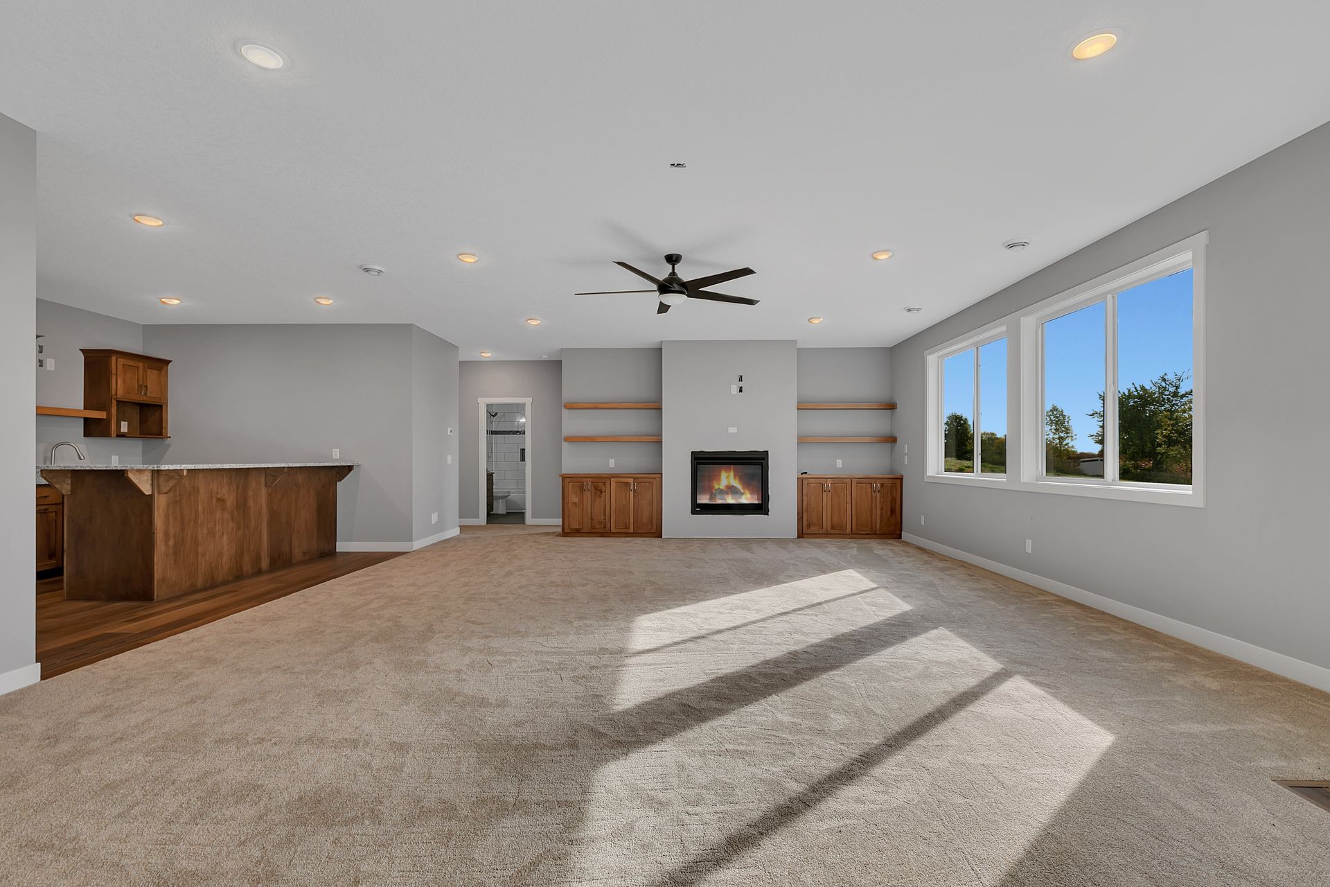 An empty living room with a fireplace and a ceiling fan.