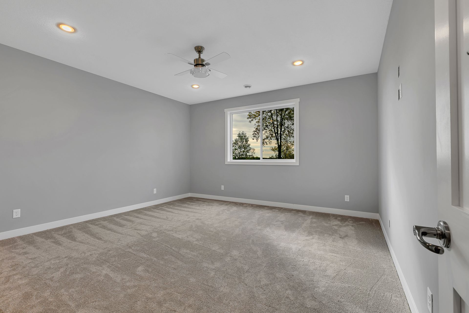 An empty bedroom with a ceiling fan and a window.