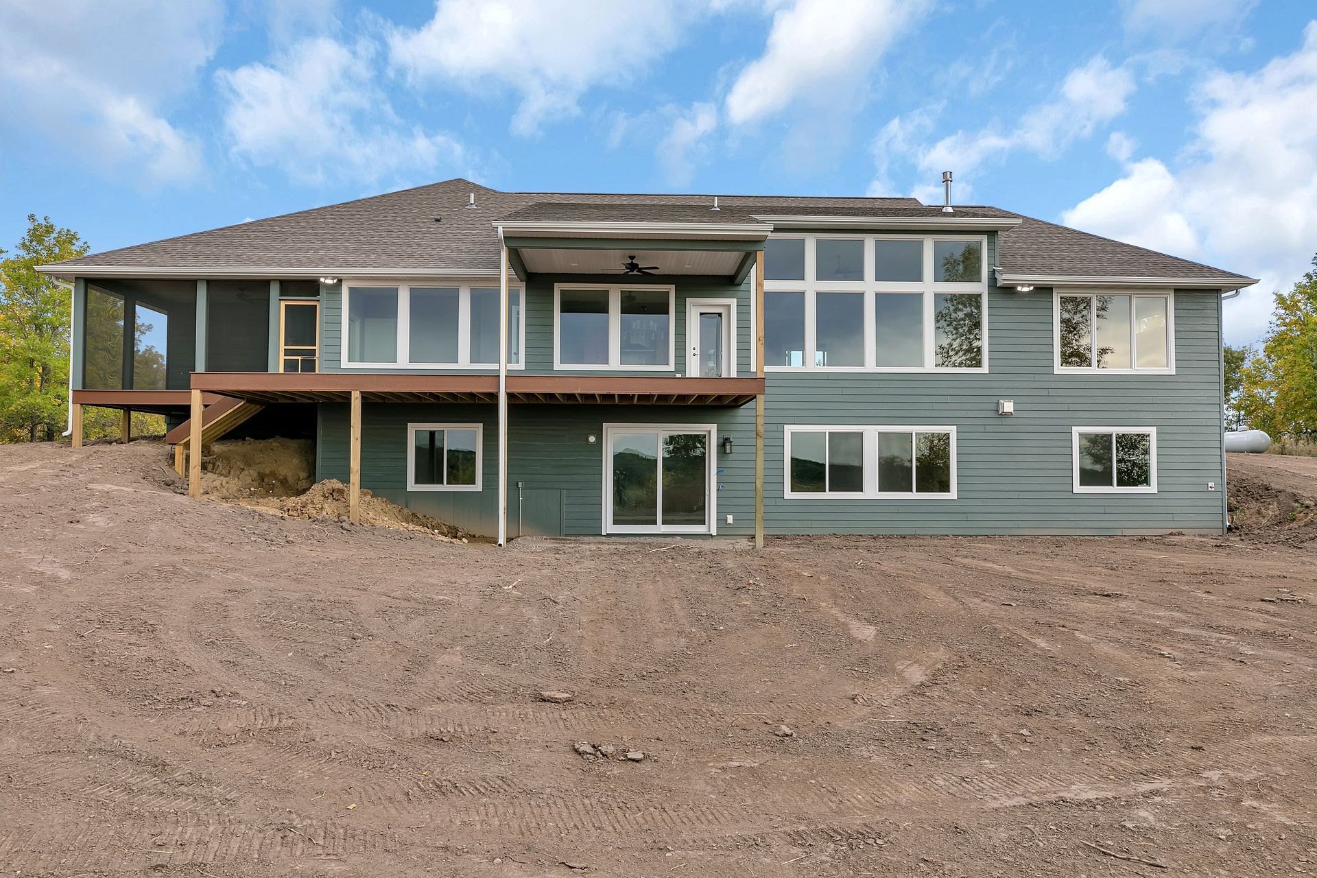 A large house with a lot of windows is sitting on top of a dirt hill