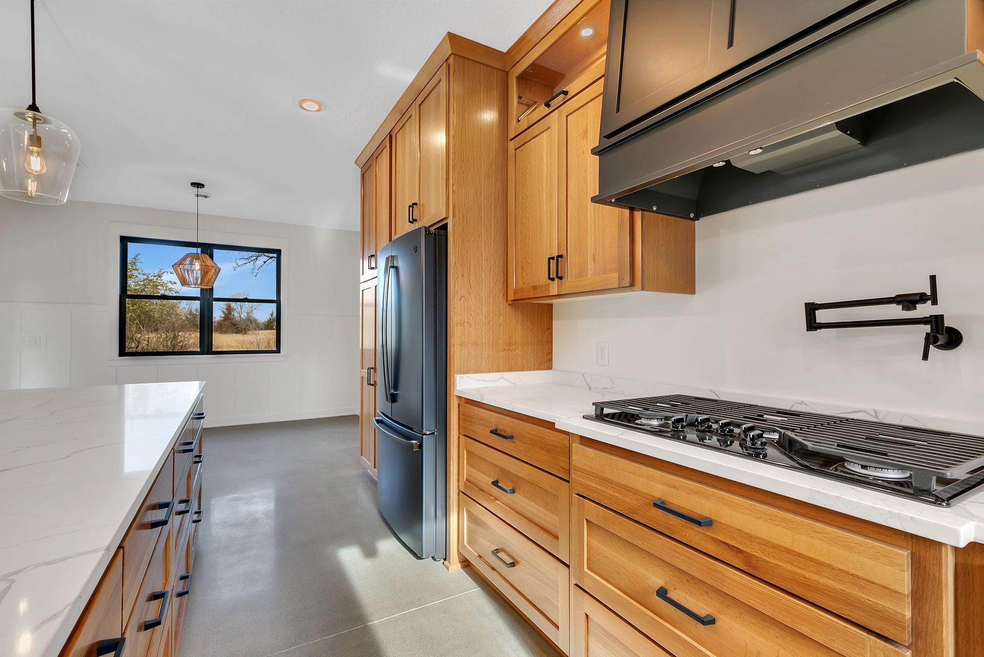 A kitchen with wooden cabinets , a stove top oven , a refrigerator , and a sink.