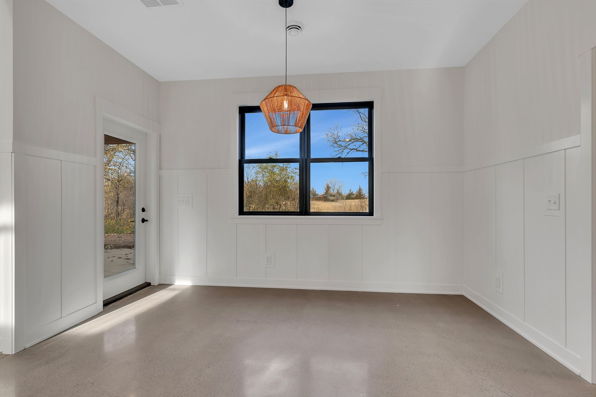 An empty room with a large window and a chandelier hanging from the ceiling.
