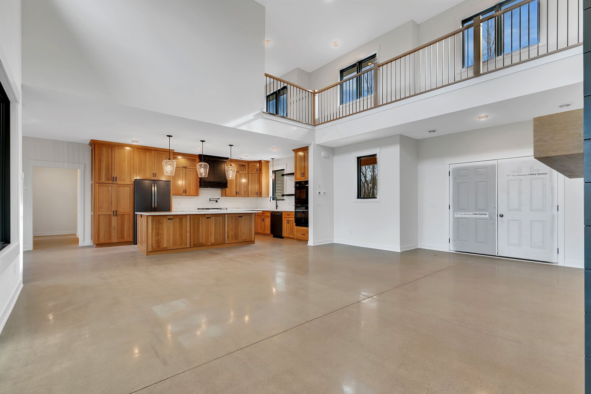 A large empty room with a kitchen and a balcony.