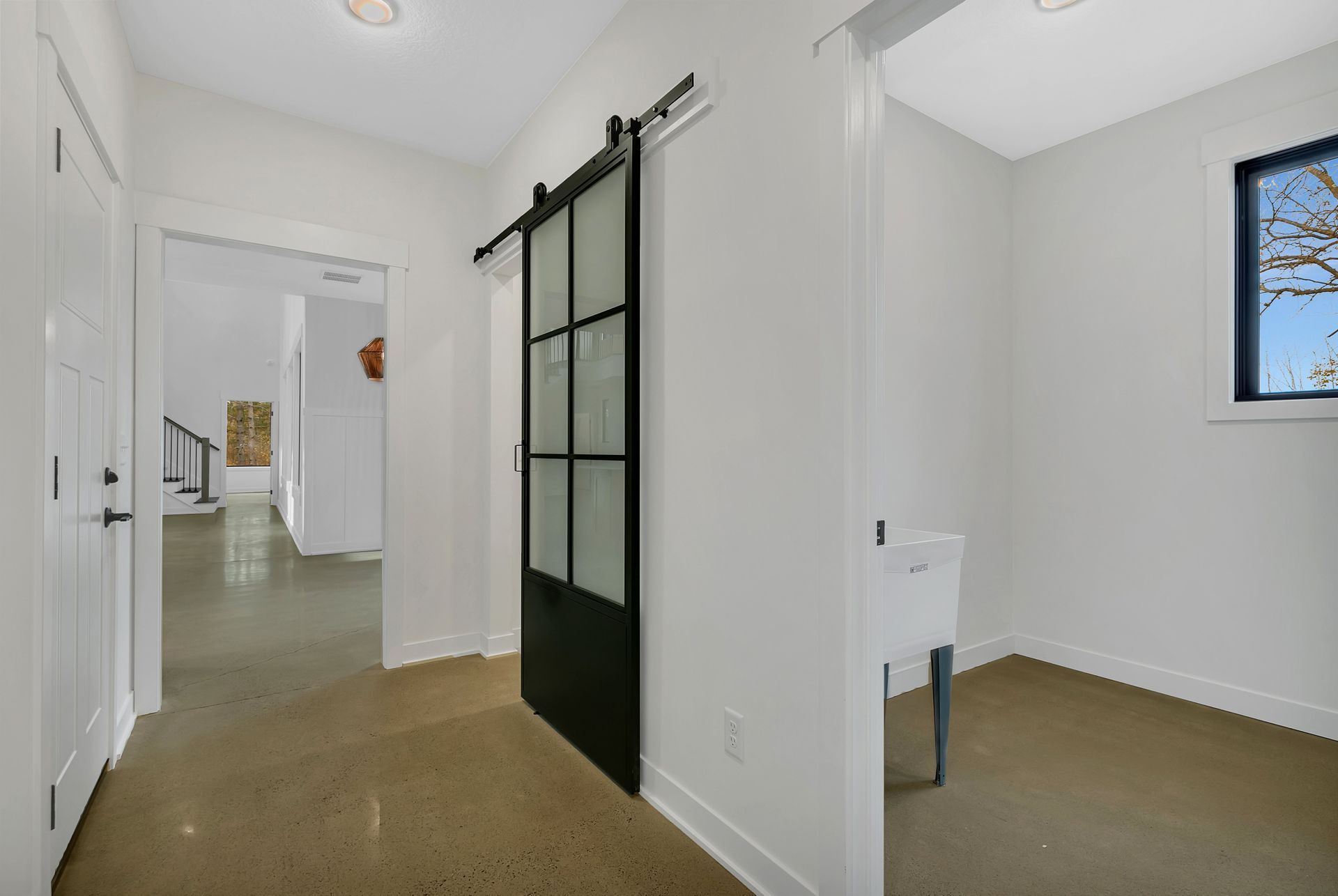 A hallway with a sliding barn door and a window.